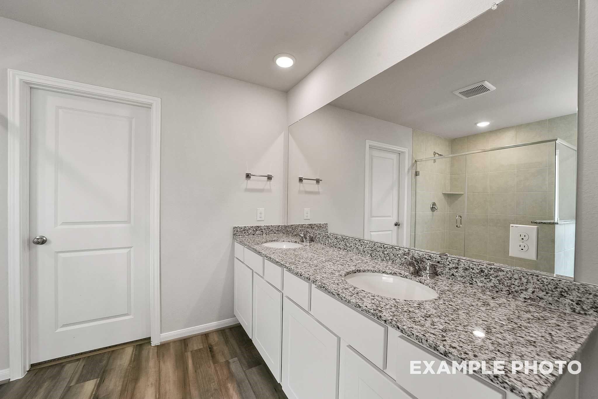 Modern master bathroom featuring double granite vanity, white cabinets, frameless shower in Davidson Homes The Tierra B, Beasley TX