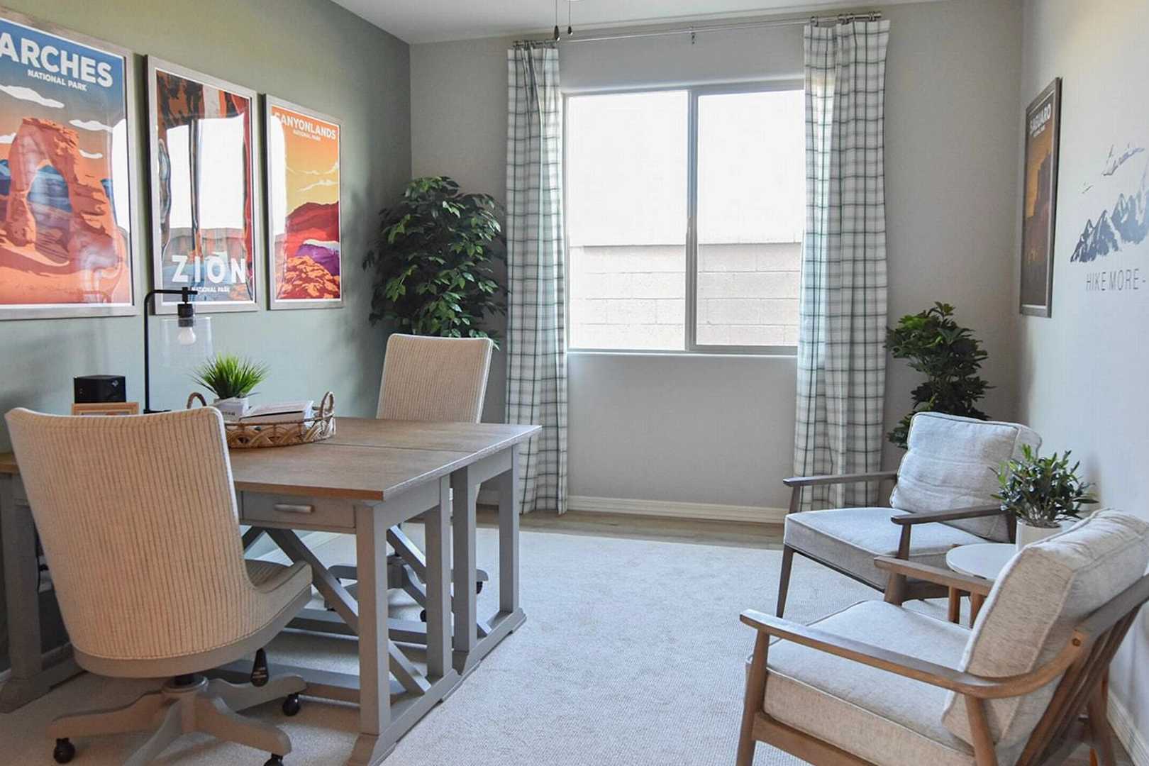 Cozy home office at North Ridge Pronghorn Ranch in Prescott Valley AZ with wooden desk, neutral walls, desert park posters and potted plants