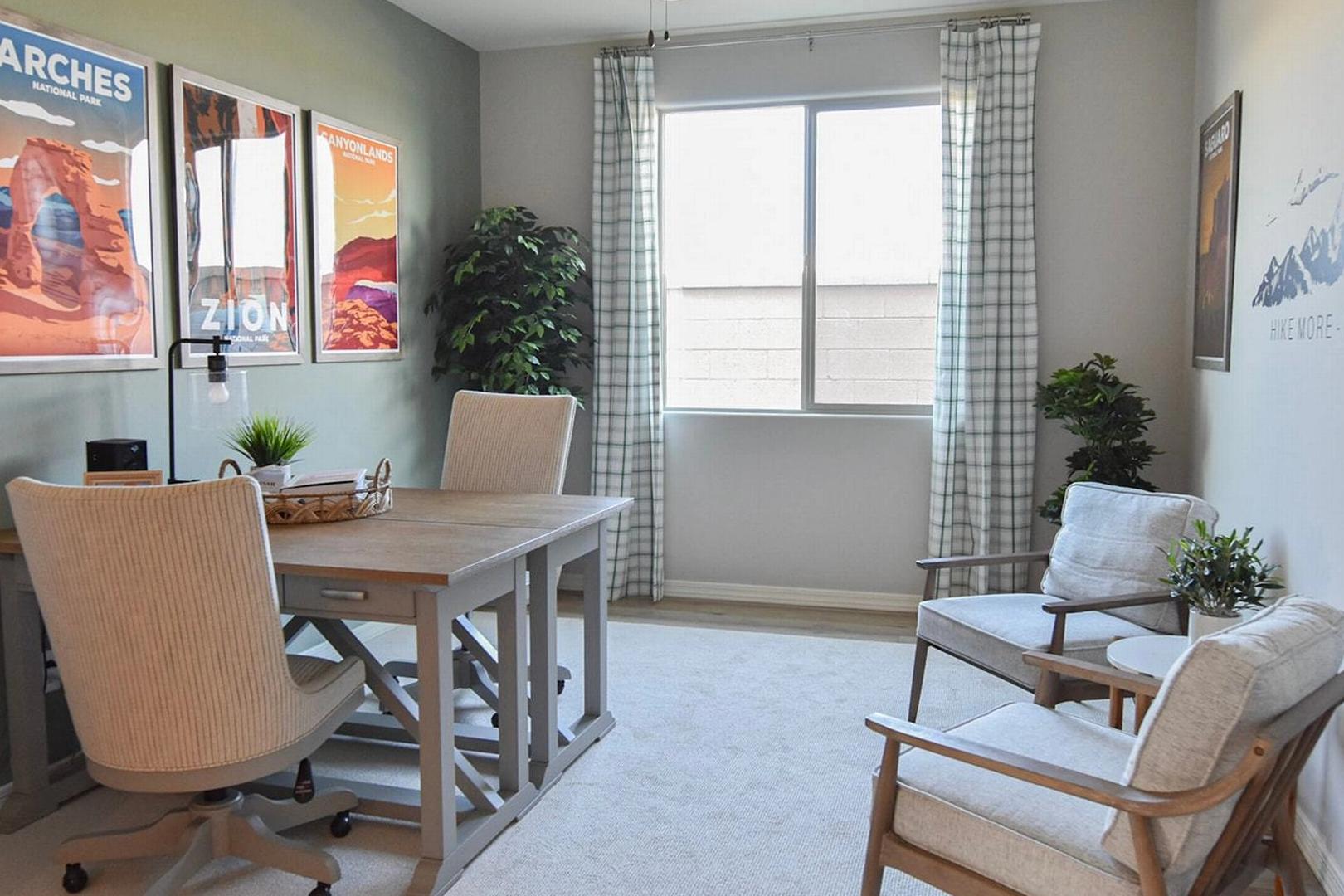 Cozy home office at North Ridge Pronghorn Ranch in Prescott Valley AZ with wooden desk, neutral walls, desert park posters and potted plants