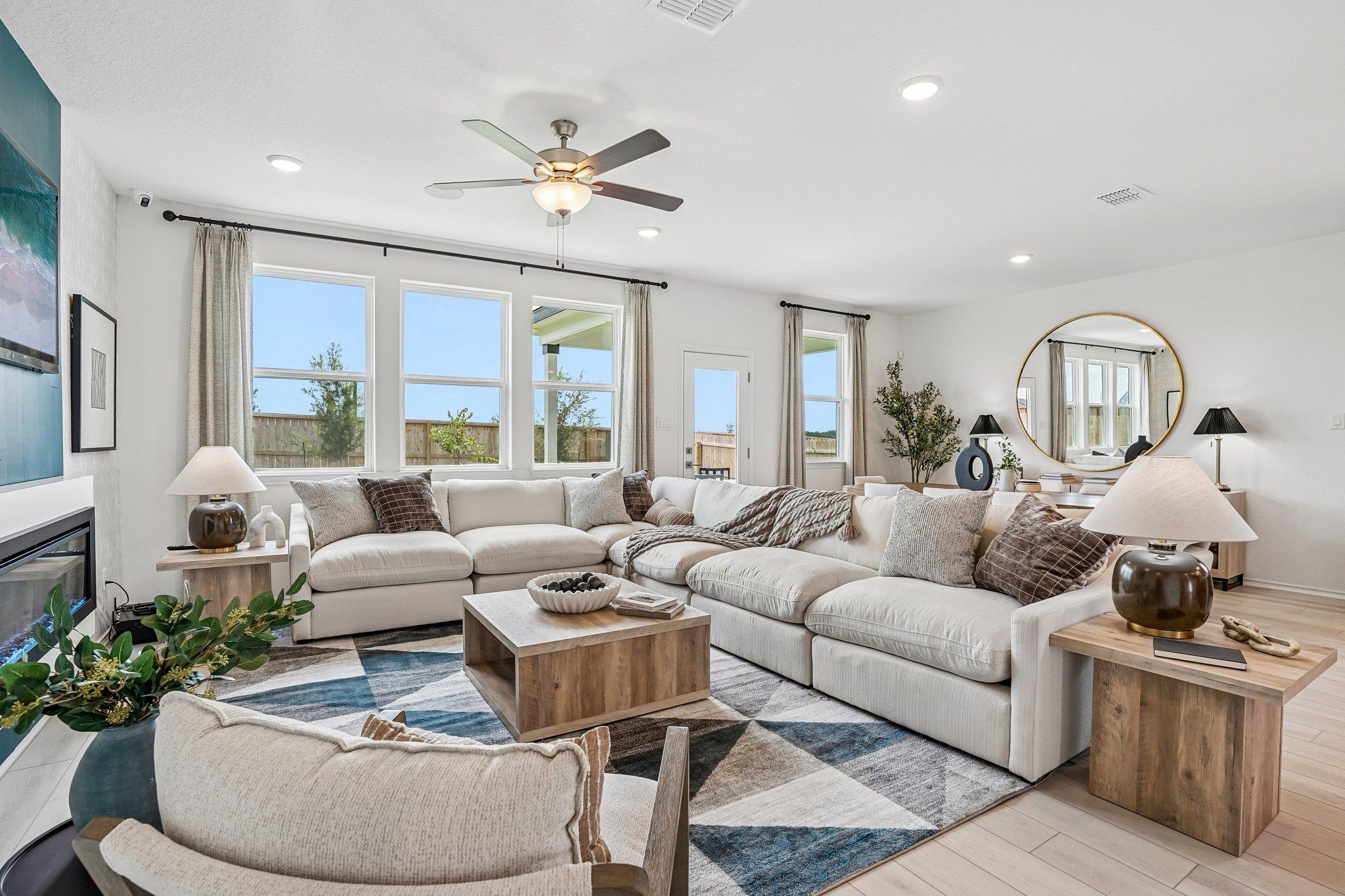Spacious living room at Morgan Meadows in San Antonio, TX, featuring a large sectional, modern fireplace, and bright windows.