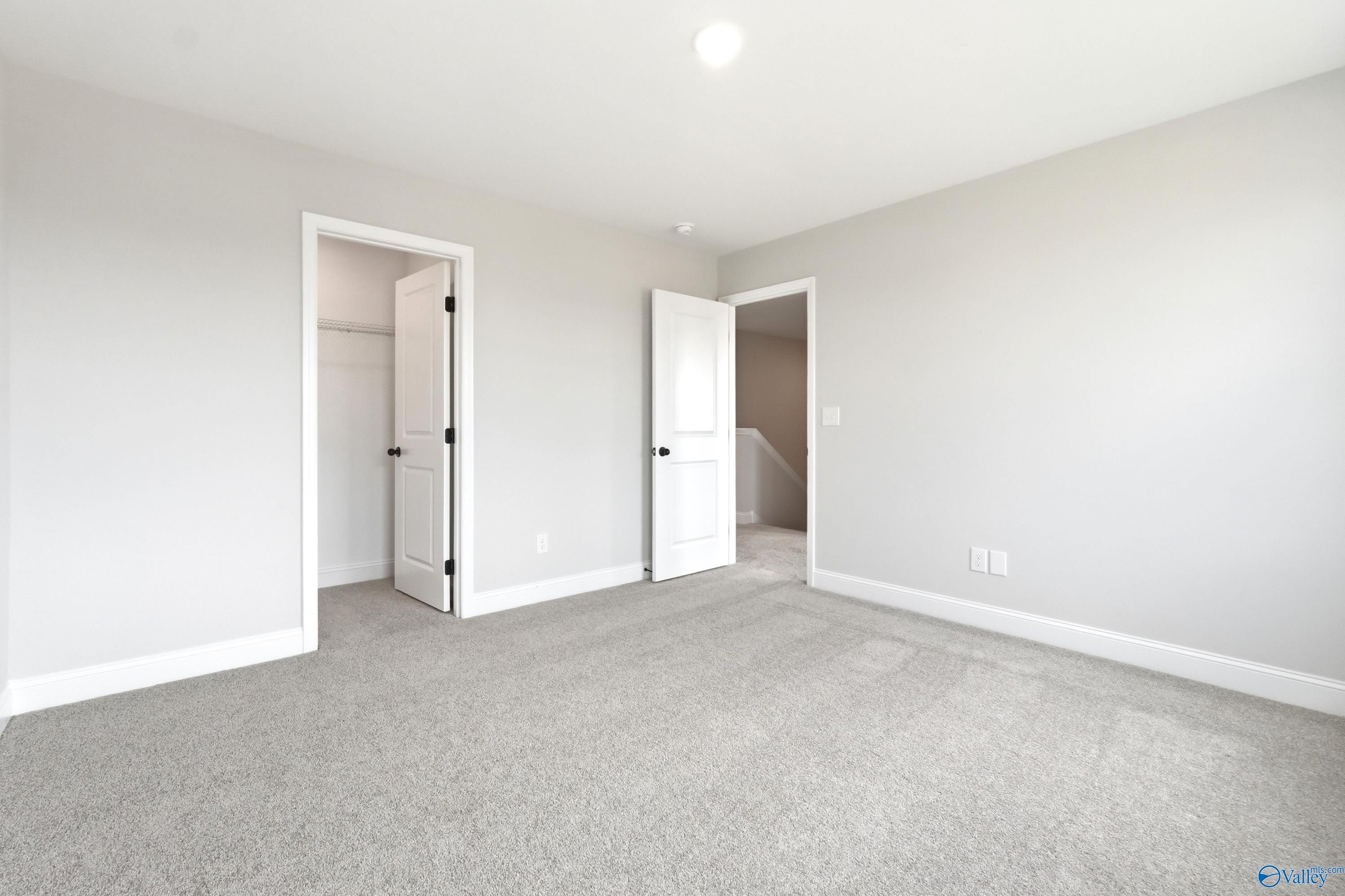 Spacious secondary bedroom with neutral carpet and walk-in closet in The Shelby A floor plan at Clearview, Hazel Green, AL.