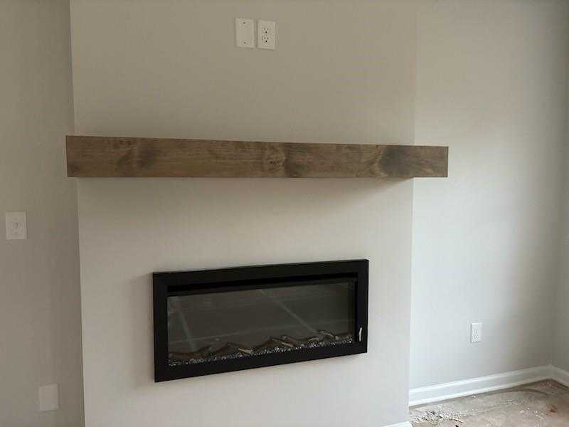Modern linear gas fireplace with rustic wood mantel in The Rabun C living room, Davidson Homes, Winder, Georgia
