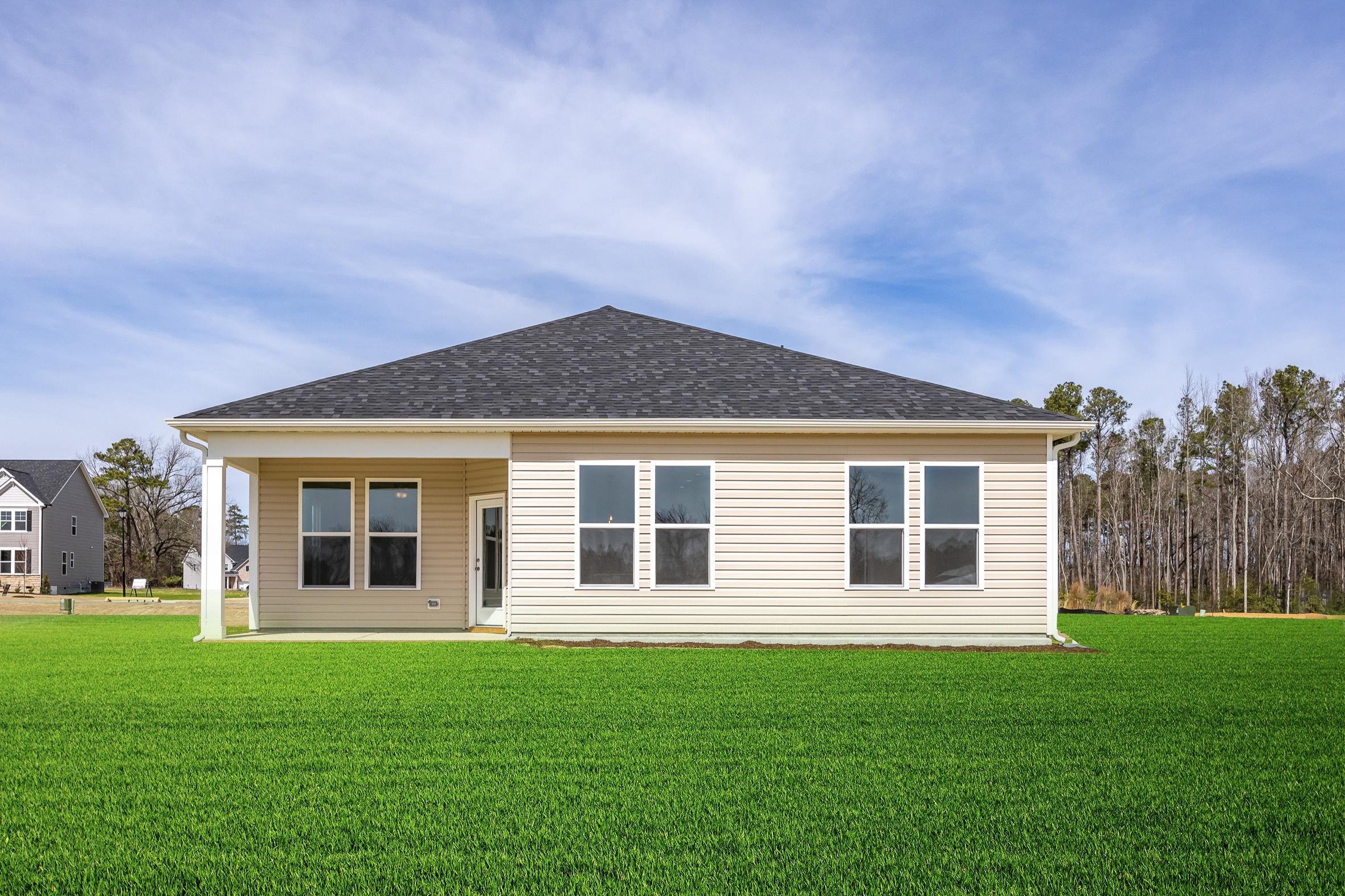 Rear elevation of The Franklin C single-story home by Davidson Homes in Lillington NC, with covered porch, beige siding, and lush green lawn
