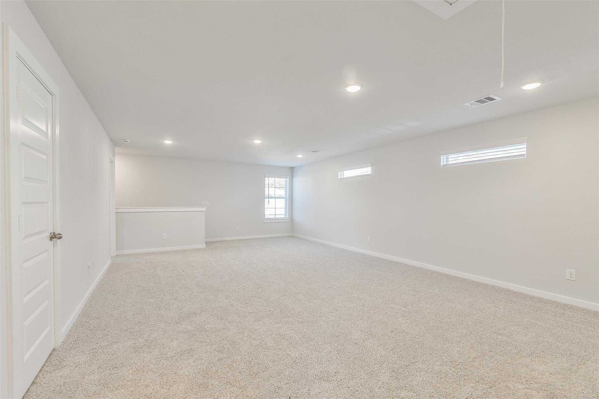 Spacious upstairs loft with beige carpet, clerestory windows, and railing in Davidson Homes The Rio Grande H, Magnolia TX