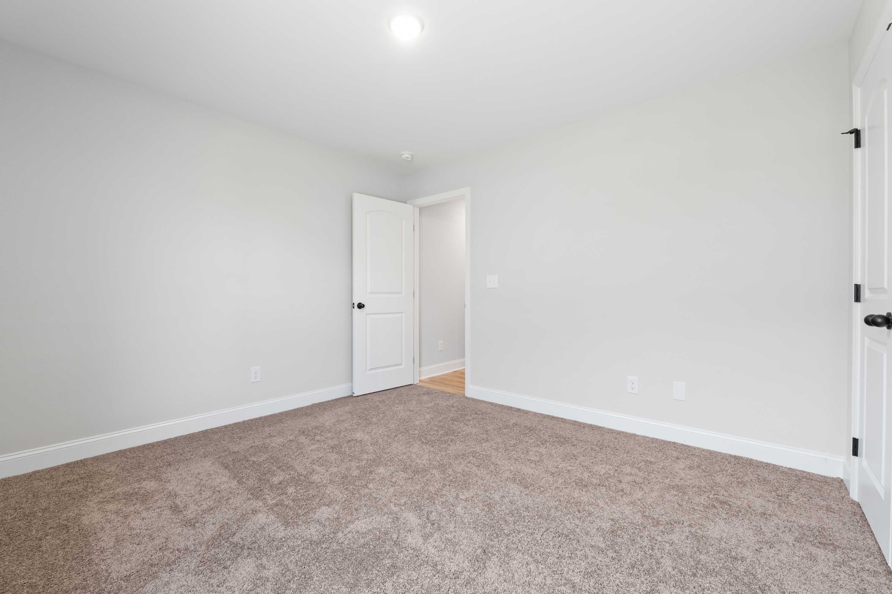 Spacious secondary bedroom in The Everett C by Davidson Homes, light gray walls, beige carpet, white doors