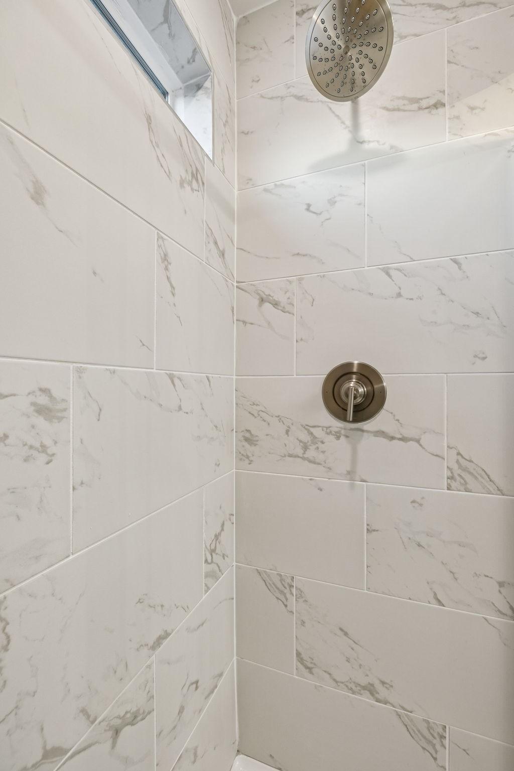 Modern walk-in shower with white marble subway tiles, rainfall showerhead, and niche in The Willow master bath, Davidson Homes