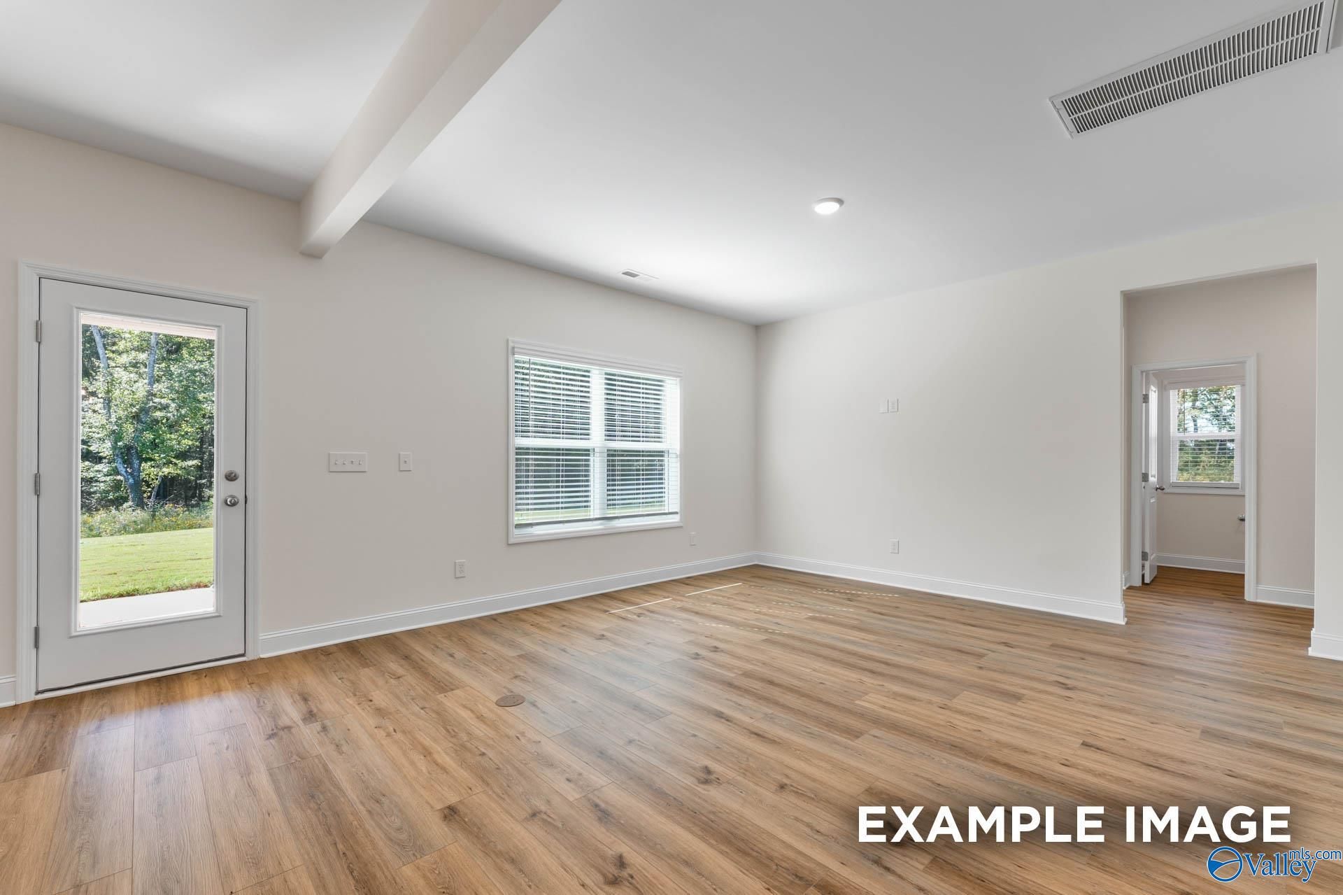 Bright sunroom with glass door to backyard, window view of trees, hardwood floors in The Shelby A home, Hazel Green, Alabama