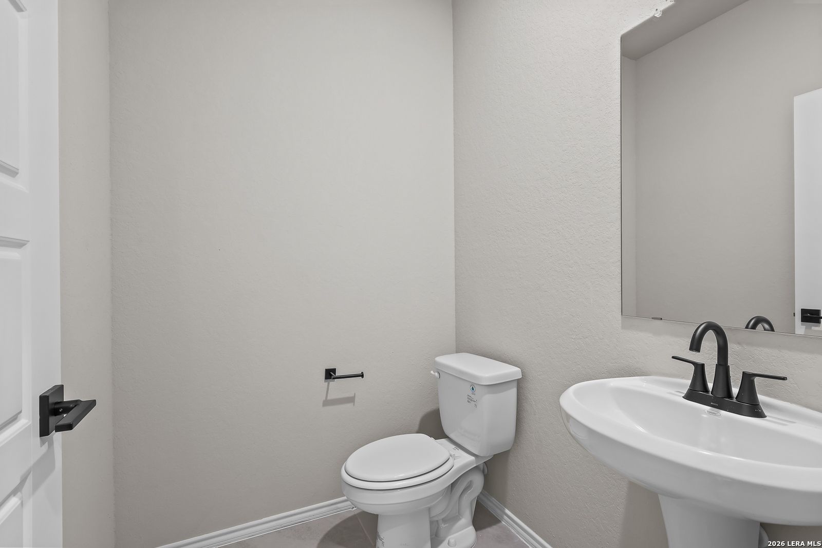 Half bathroom with pedestal sink, matte black faucet, and white toilet in Davidson Homes The Sequoia C, Royal Crest, San Antonio