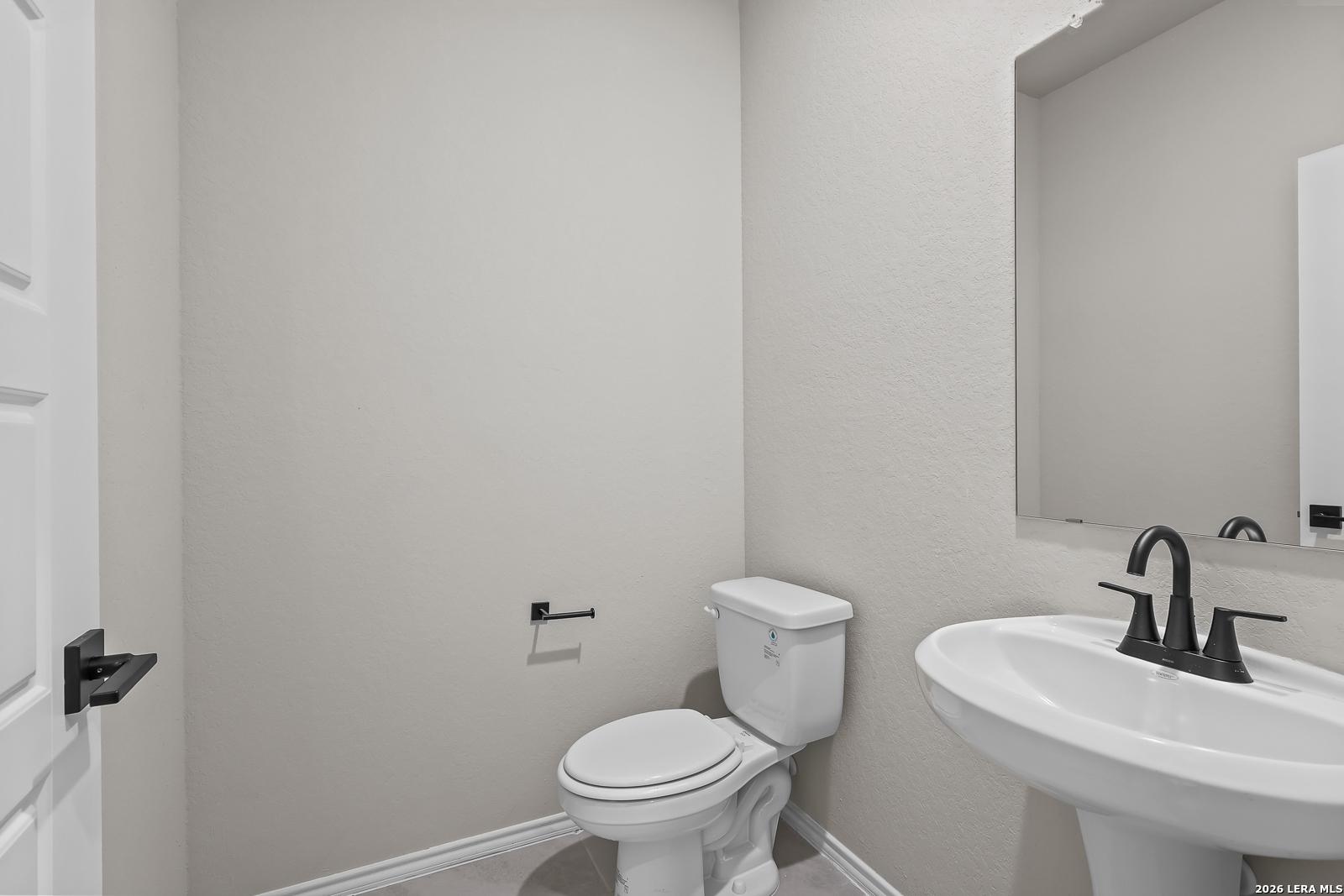 Half bathroom with pedestal sink, matte black faucet, and white toilet in Davidson Homes The Sequoia C, Royal Crest, San Antonio