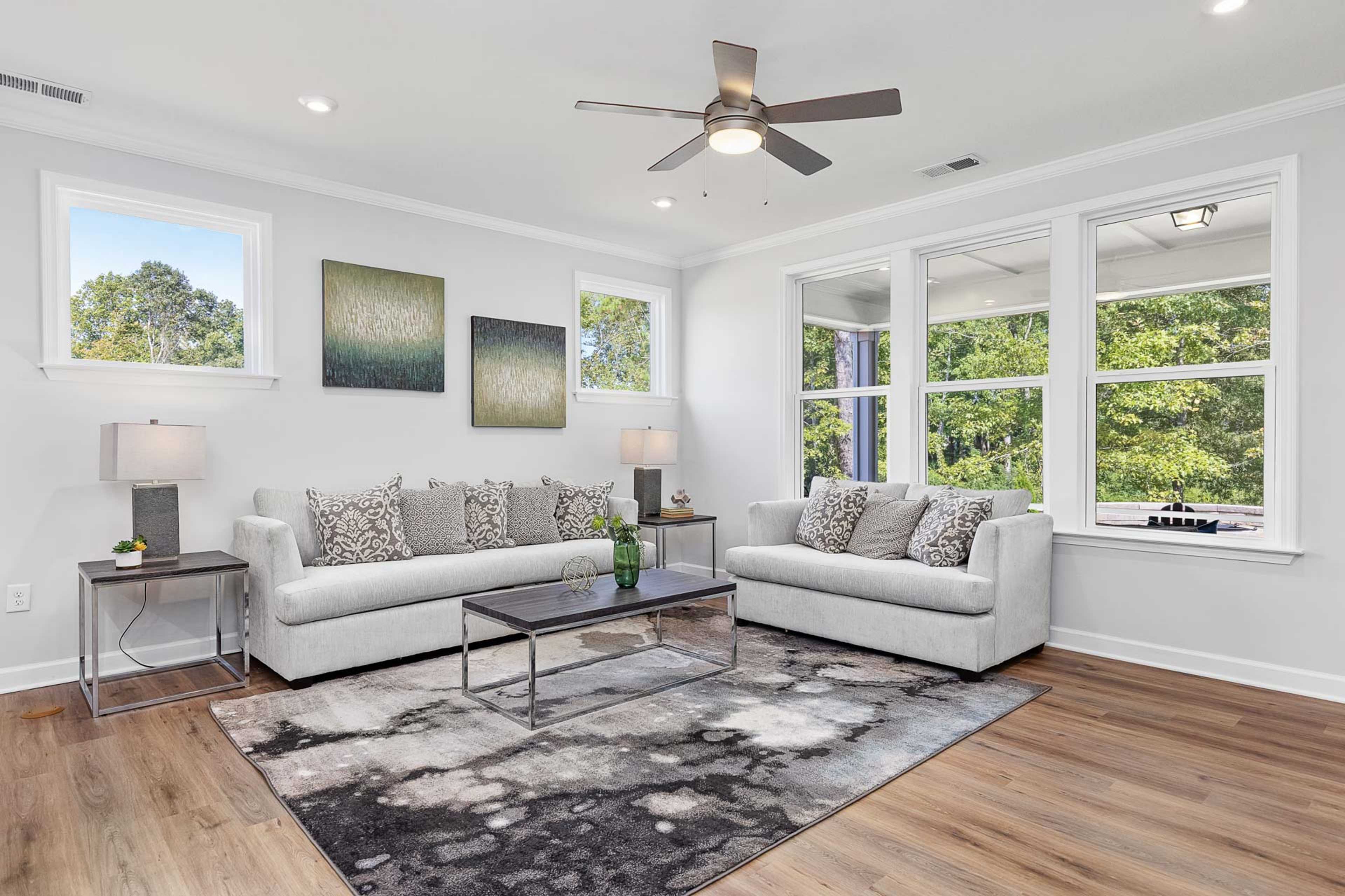 Cozy living room at Glenmere in Knightdale NC with white sofas hardwood floors large windows and abstract art