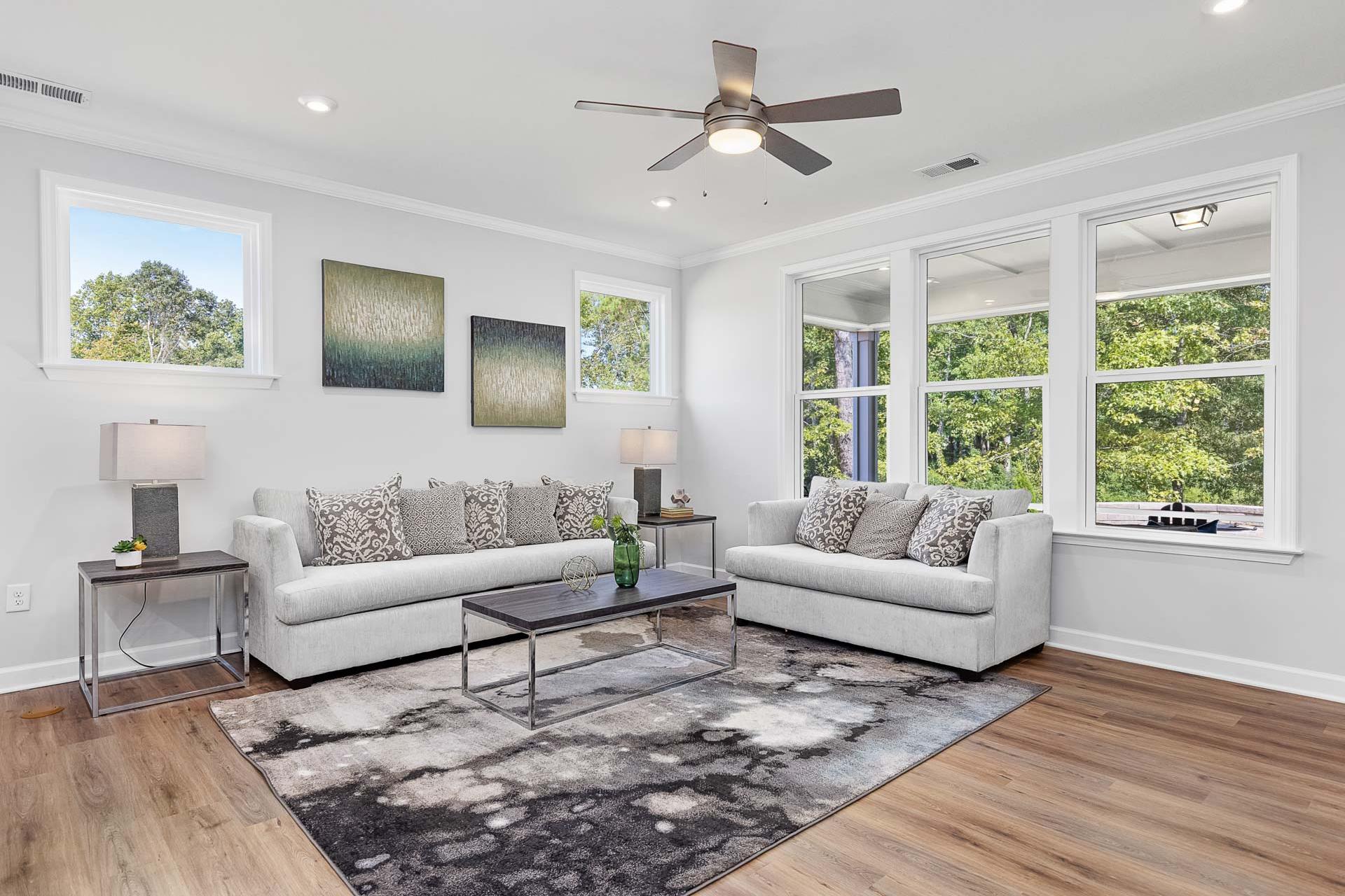 Cozy living room at Glenmere in Knightdale NC with white sofas hardwood floors large windows and abstract art