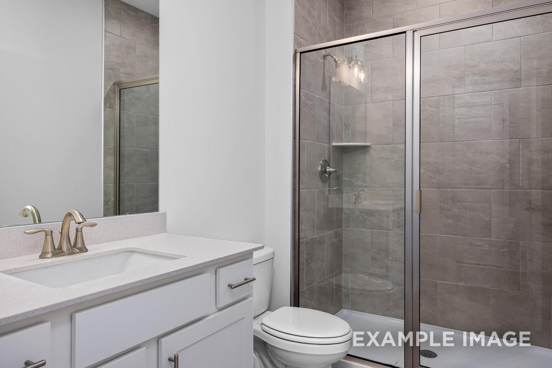 Modern master bathroom in The Preston B: white double vanity, frameless glass shower, gray tile accents, Wendell NC