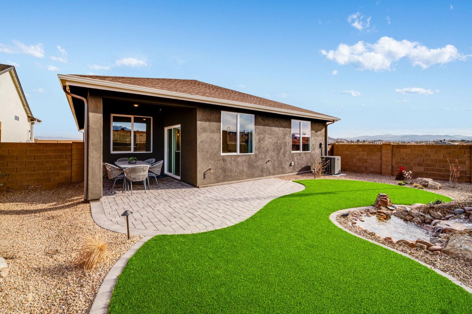 Spacious backyard of The Newport C home with covered patio, artificial turf lawn, rock water feature in Prescott AZ