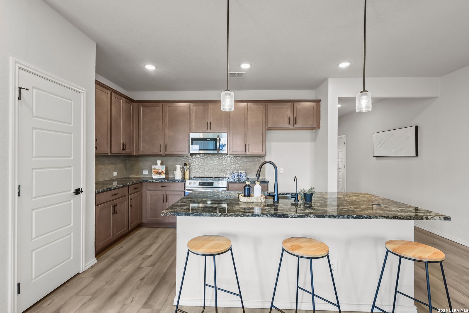 Modern kitchen featuring granite island, shaker wood cabinets, stainless appliances in The Daphne H by Davidson Homes, Seguin, TX
