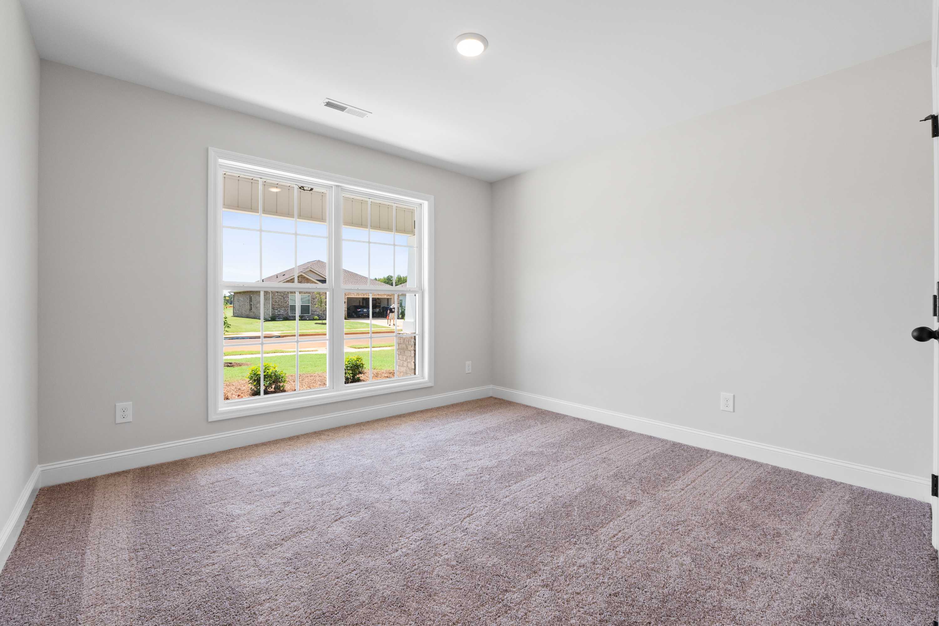 Spacious secondary bedroom in The Everett C with gray walls, beige carpet, large window overlooking green yard
