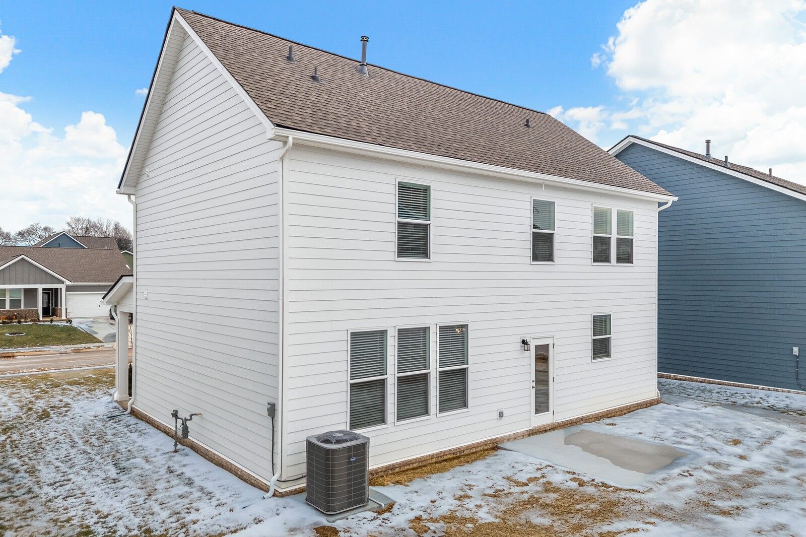 Two-story white home exterior with two-car garage, side entry, and AC unit in Davidson Homes The Gordon C, Sage Farms, White House, TN