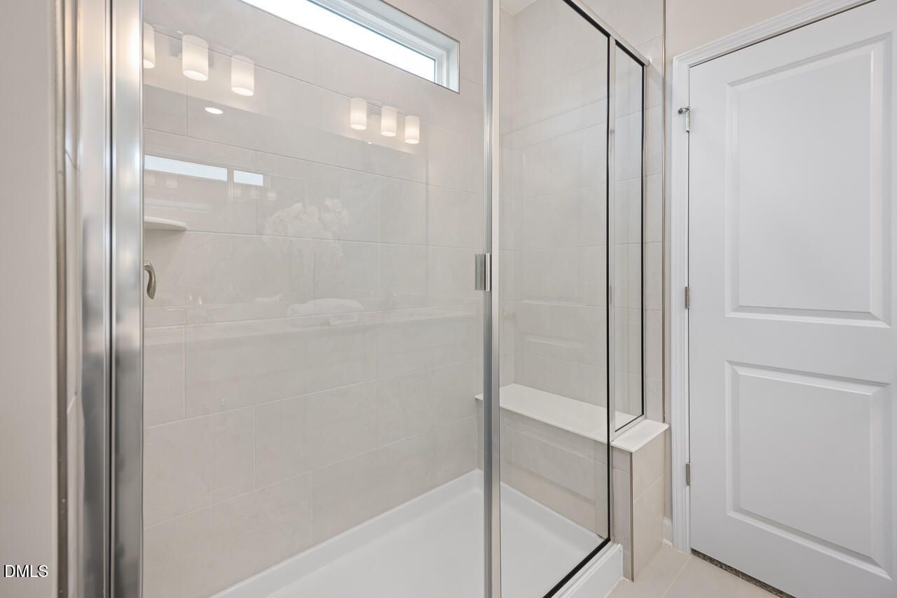 Modern walk-in shower with frameless glass doors, white subway tile, and built-in bench in master bath, Davidson Homes The Carter C, Lillington NC