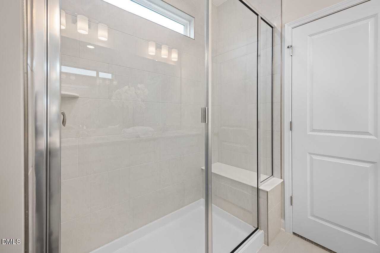 Modern walk-in shower with frameless glass doors, white subway tile, and built-in bench in master bath, Davidson Homes The Carter C, Lillington NC