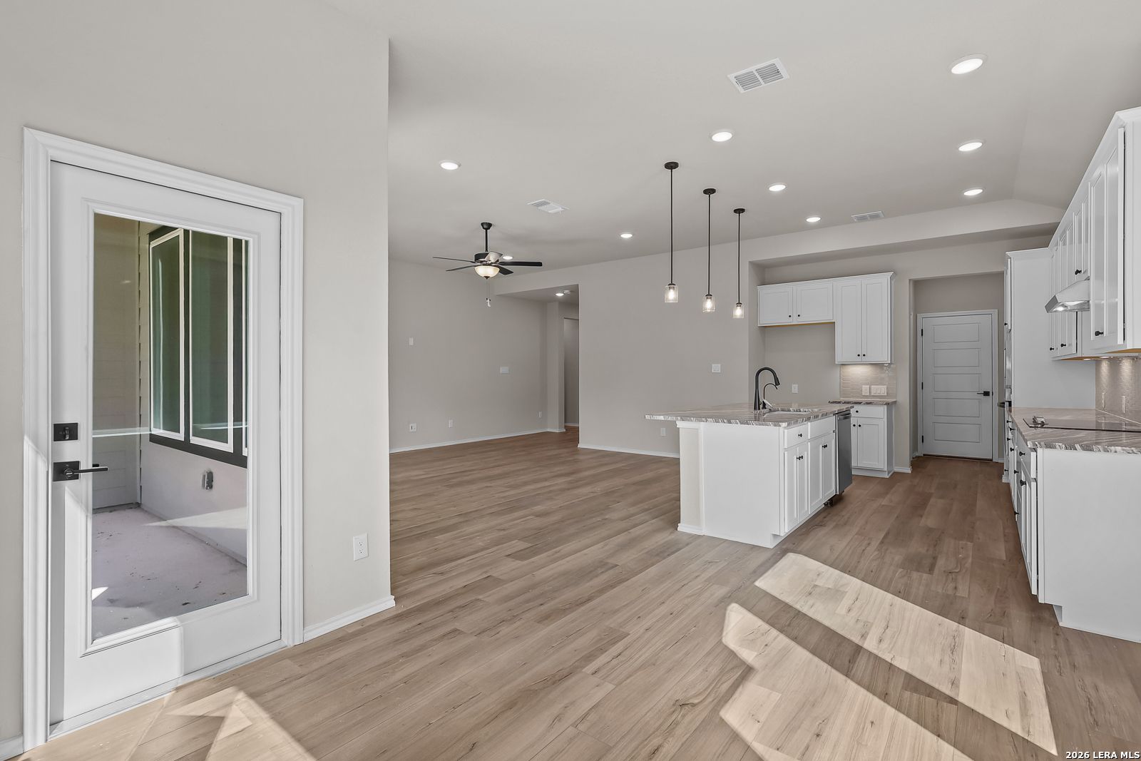 Open-concept kitchen with white cabinetry, island, and pendant lights in Davidson Homes The Sequoia C, Royal Crest, San Antonio