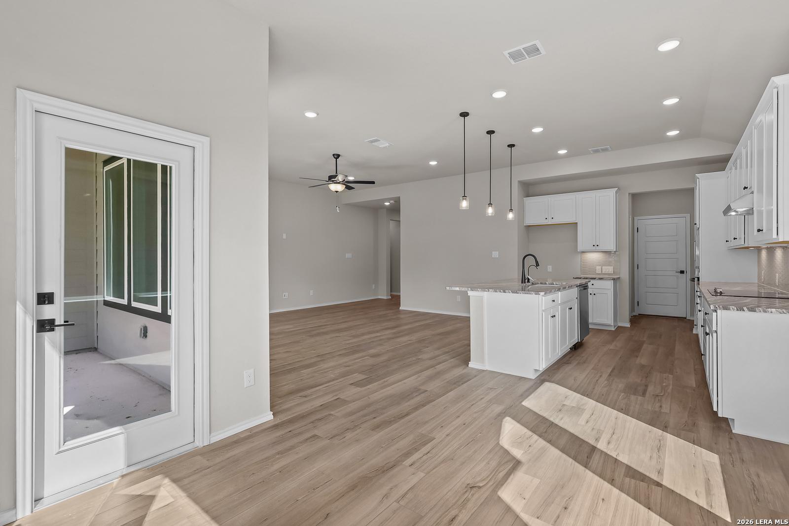 Open-concept kitchen with white cabinetry, island, and pendant lights in Davidson Homes The Sequoia C, Royal Crest, San Antonio