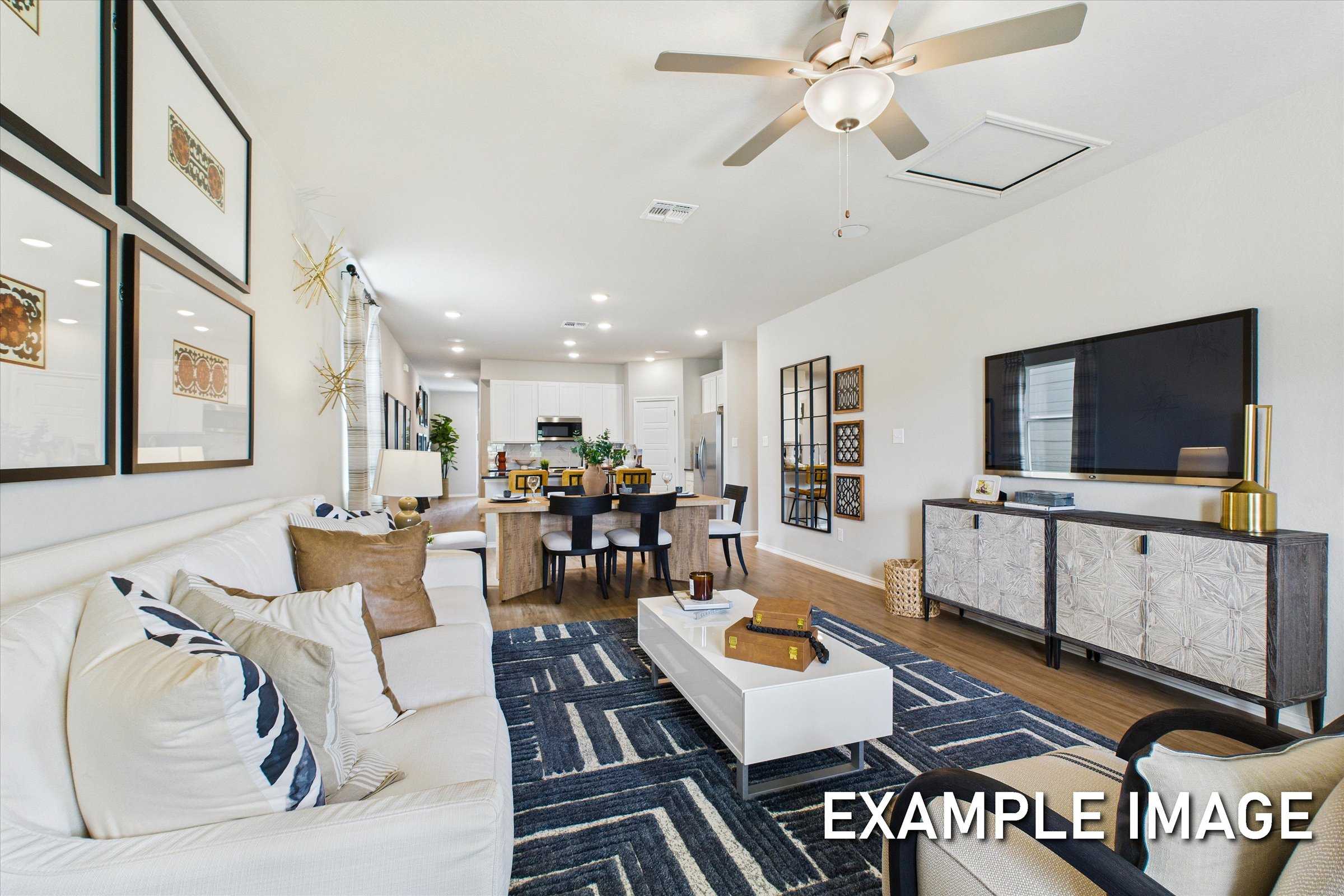 Open-concept living room with white sectional sofa, dining table, and modern kitchen in Davidson Homes The Sabine C, San Antonio