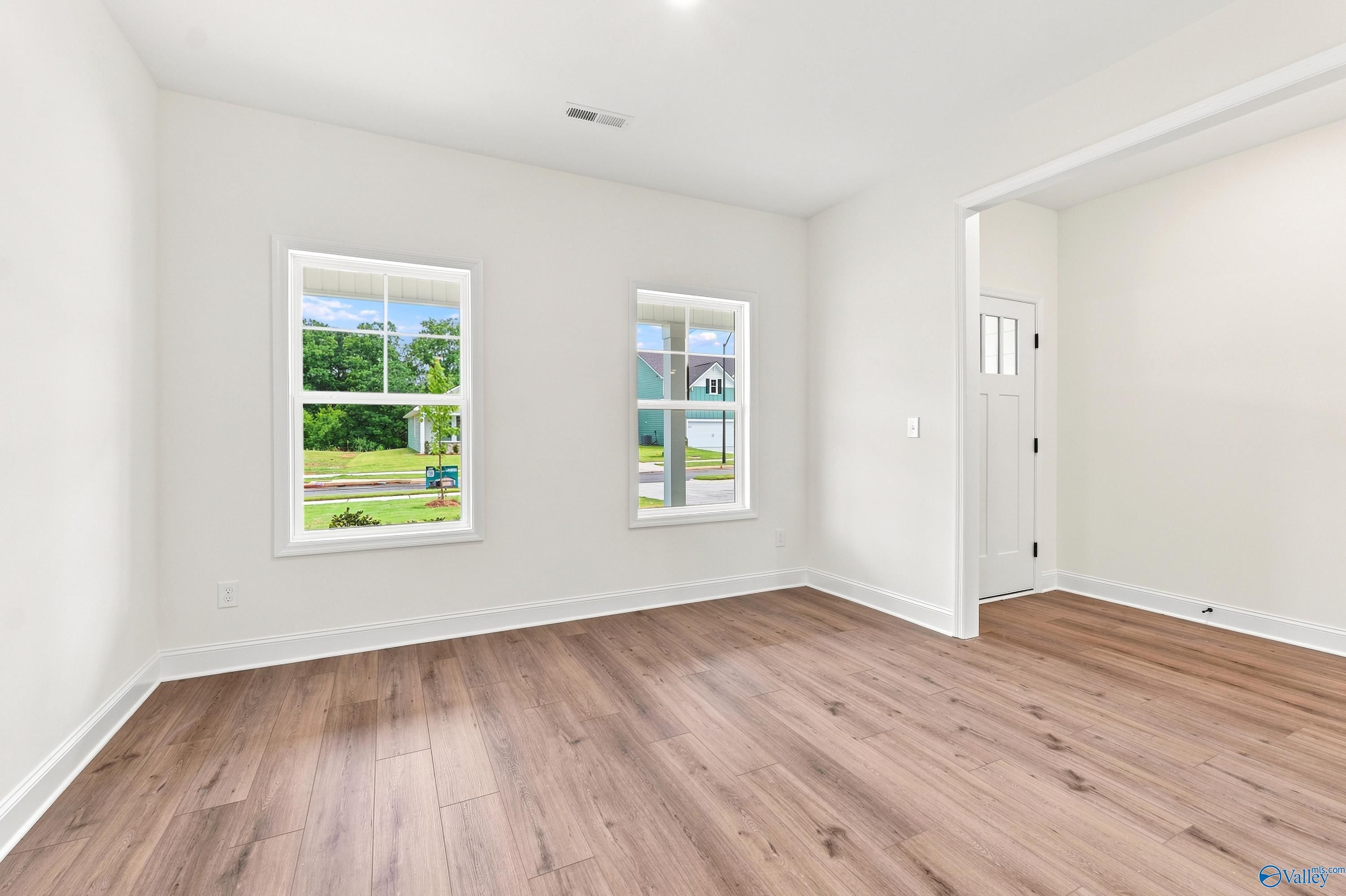 Bright bedroom with wood-look flooring and white walls in The Shelby D floor plan at Noble Ridge, Cullman, Alabama.
