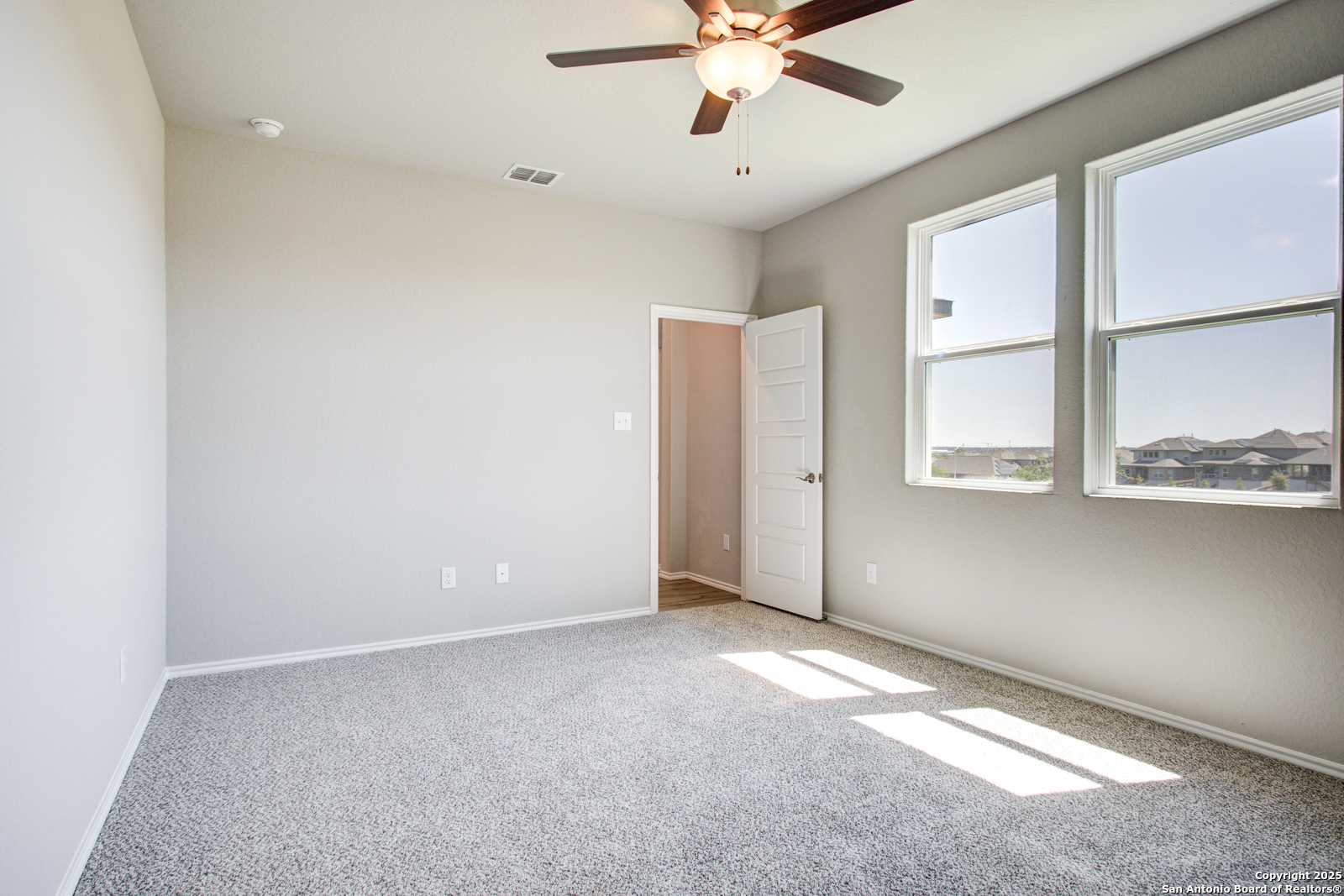 Bright secondary bedroom with ceiling fan, large sunny windows, and plush carpet in Davidson Homes The Douglas G, San Antonio