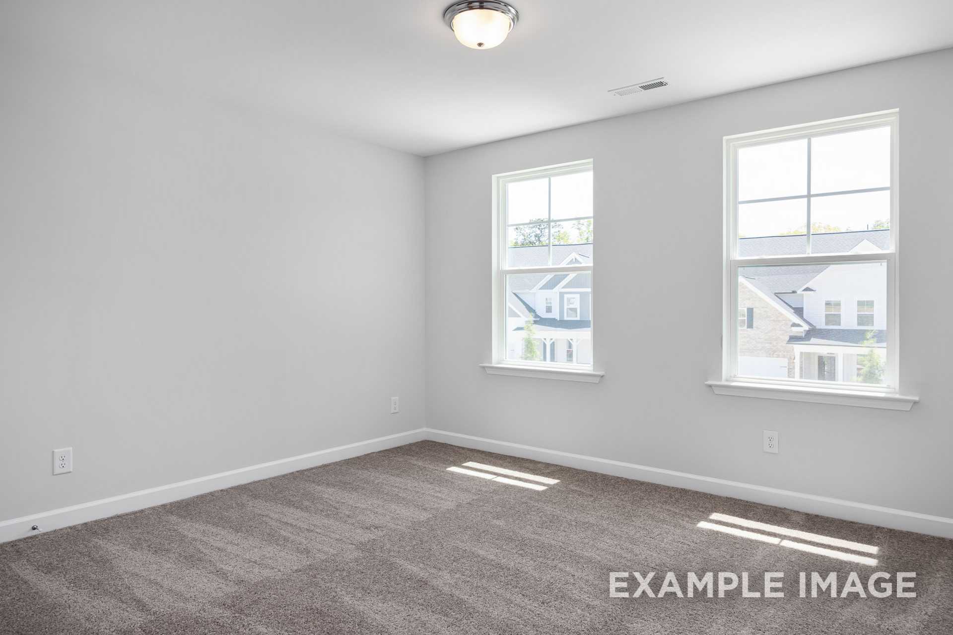 Spacious empty master bedroom in The Gavin C with gray carpet, white walls, double windows, and natural light