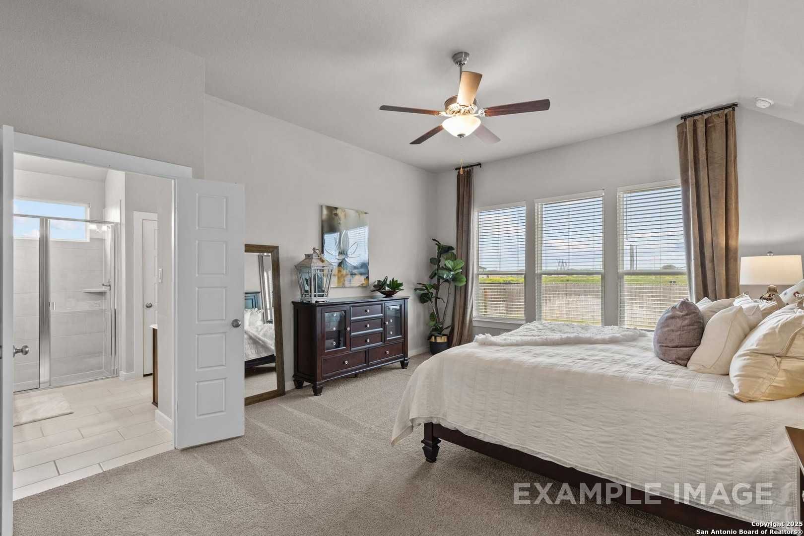 Elegant master bedroom with king bed, wood dresser, mirror, and en-suite bath in Davidson Homes The Collin B, Seguin, Texas