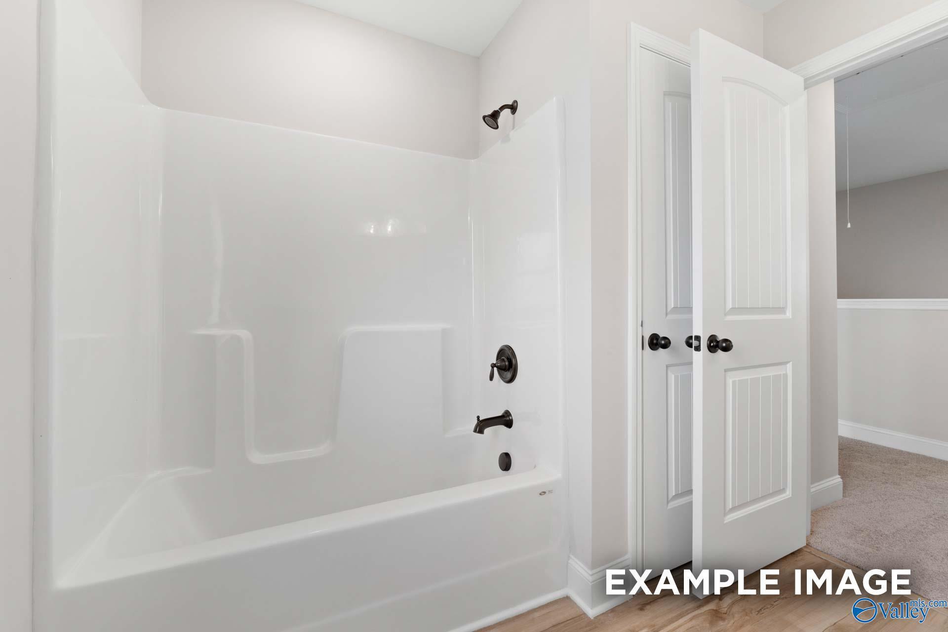 Modern bathroom with white tub-shower combo and linen closet in The Shelby B floor plan, Jaguar Hills, Huntsville.