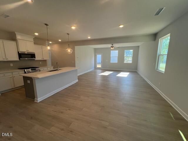 Modern open-concept kitchen featuring white cabinets, quartz island, stainless appliances in The Adalynn B by Davidson Homes, Lillington, NC