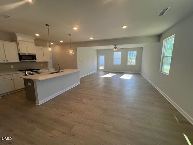 Modern open-concept kitchen featuring white cabinets, quartz island, stainless appliances in The Adalynn B by Davidson Homes, Lillington, NC