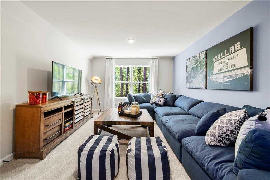 Cozy media room with blue L-shaped sectional sofa, mounted TV, wooden entertainment center, and Dallas Texas wall art in Hickory B home, Riverwood