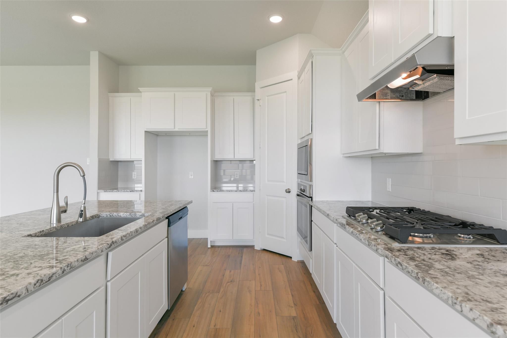 Modern white kitchen with granite countertops, stainless appliances, and gas range in Davidson Homes The Edward A, Texas City