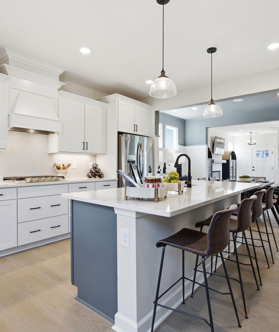 Spacious white kitchen with quartz island, stainless appliances, and French doors at Forestville Yard in Knightdale NC