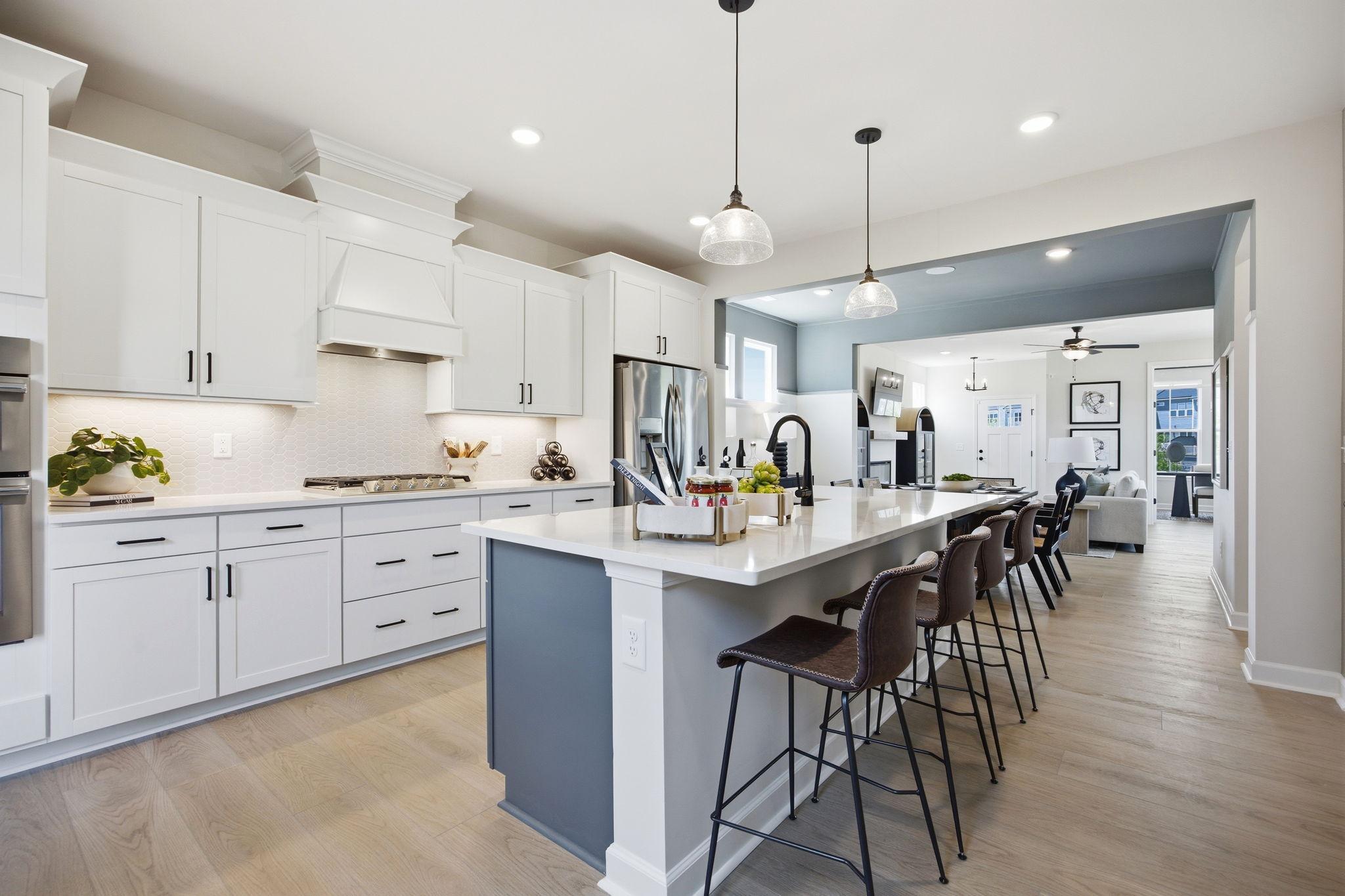 Spacious white kitchen with quartz island, stainless appliances, and French doors at Forestville Yard in Knightdale NC