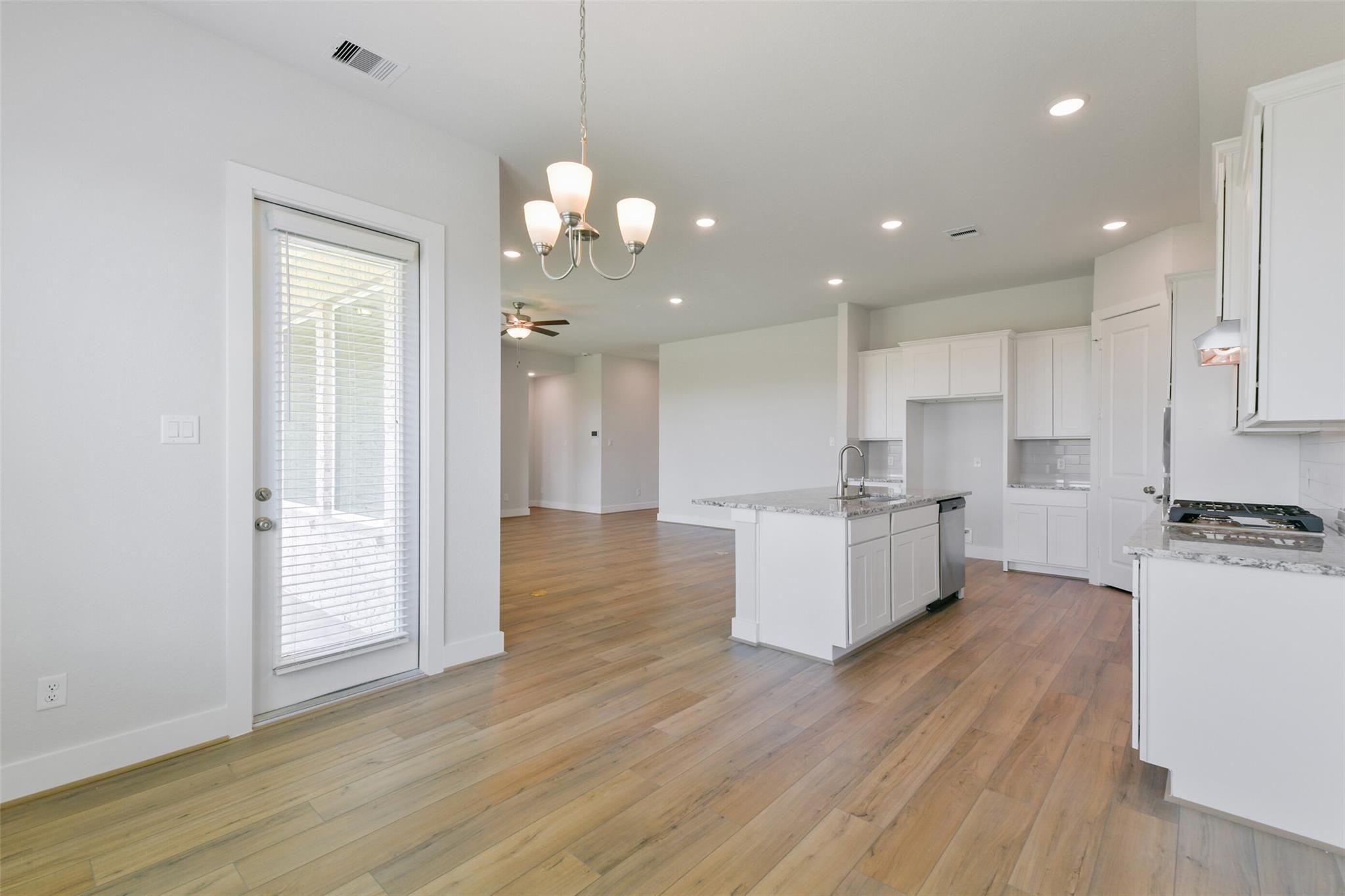 Open-concept kitchen with white island sink, dishwasher, hardwood floors in Davidson Homes The Edward A, Lago Mar, Texas City