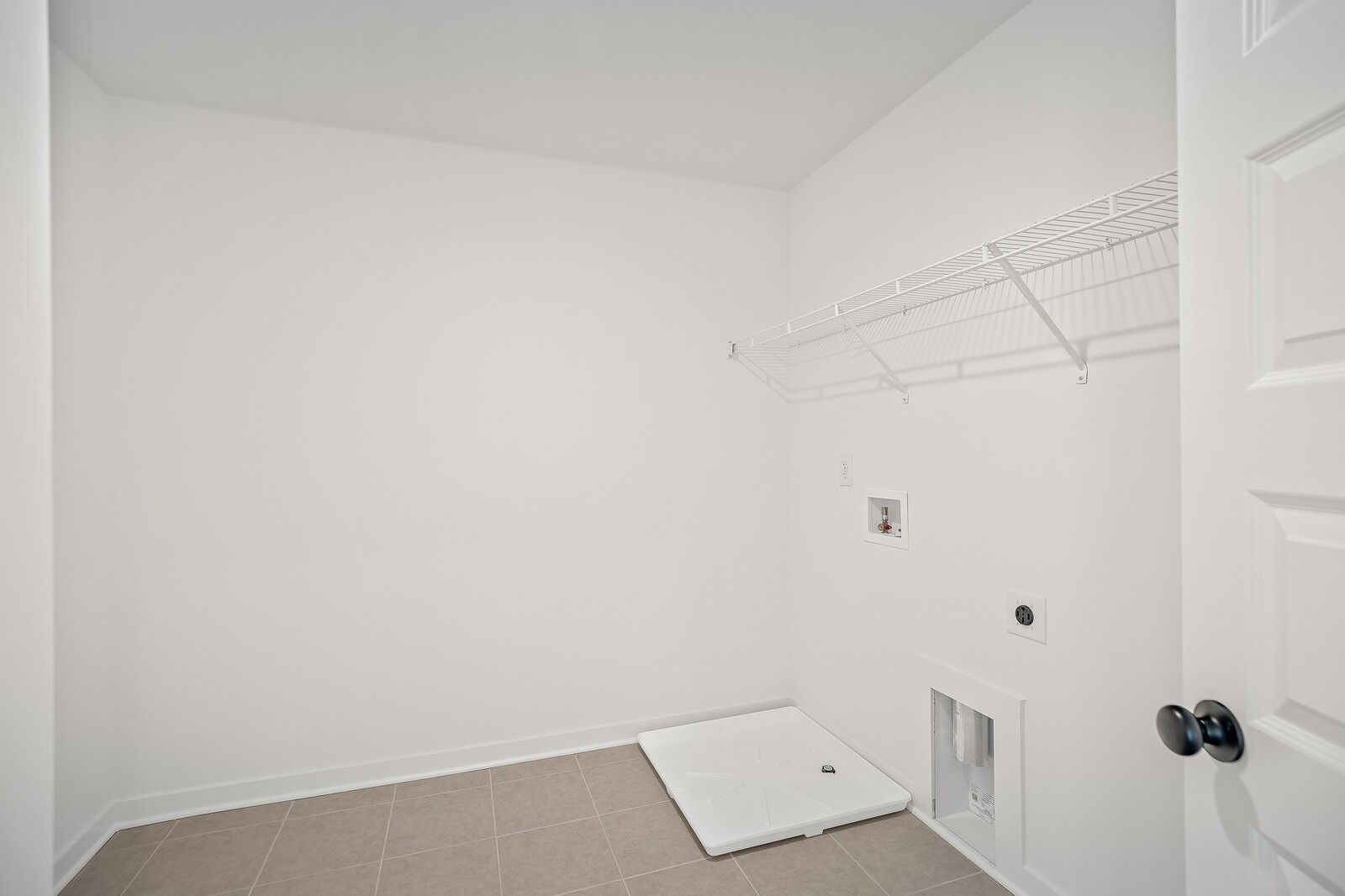 Bright laundry room with wire shelving, utility sink, and washer hookups in Davidson Homes The Logan C, Gallatin, TN