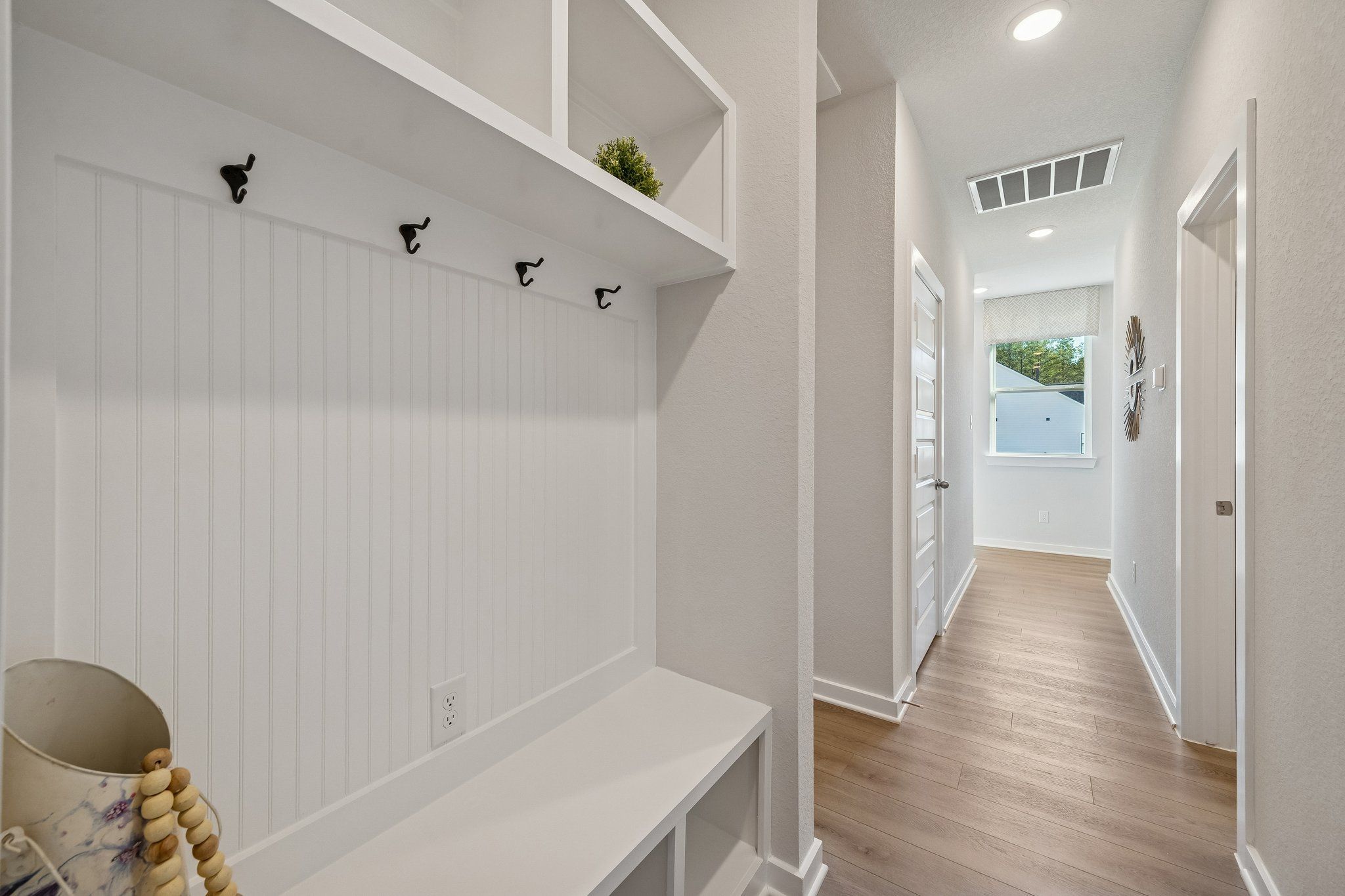 Spacious mudroom with white shiplap walls, built-in bench, hooks and shelves at Spring Branch Crossing in Conroe, Texas
