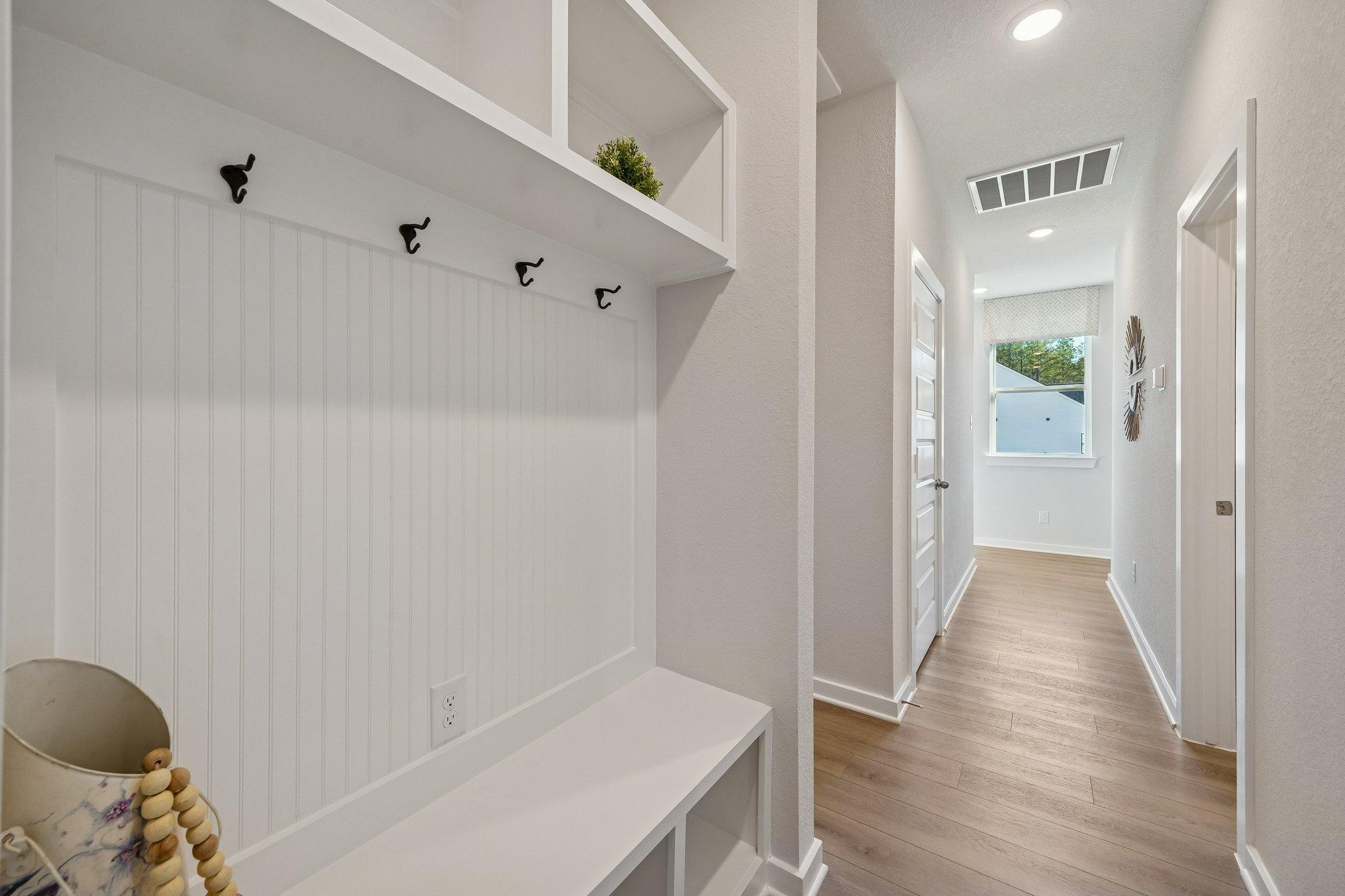 Spacious mudroom with white shiplap walls, built-in bench, hooks and shelves at Spring Branch Crossing in Conroe, Texas