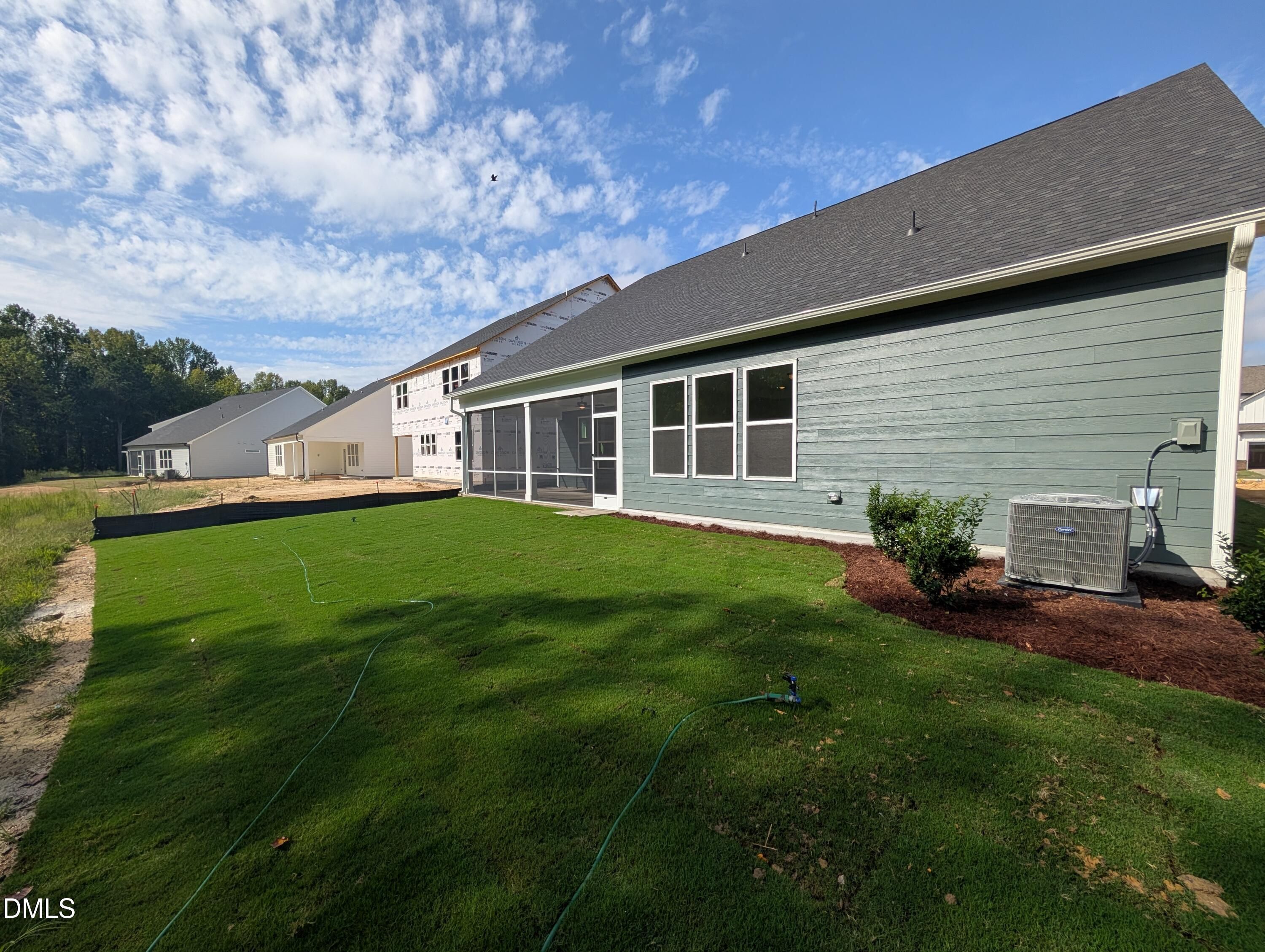 Rear exterior of Davidson Homes' The Magnolia A with screened porch, green siding, and spacious backyard in Wendell Ridge, NC