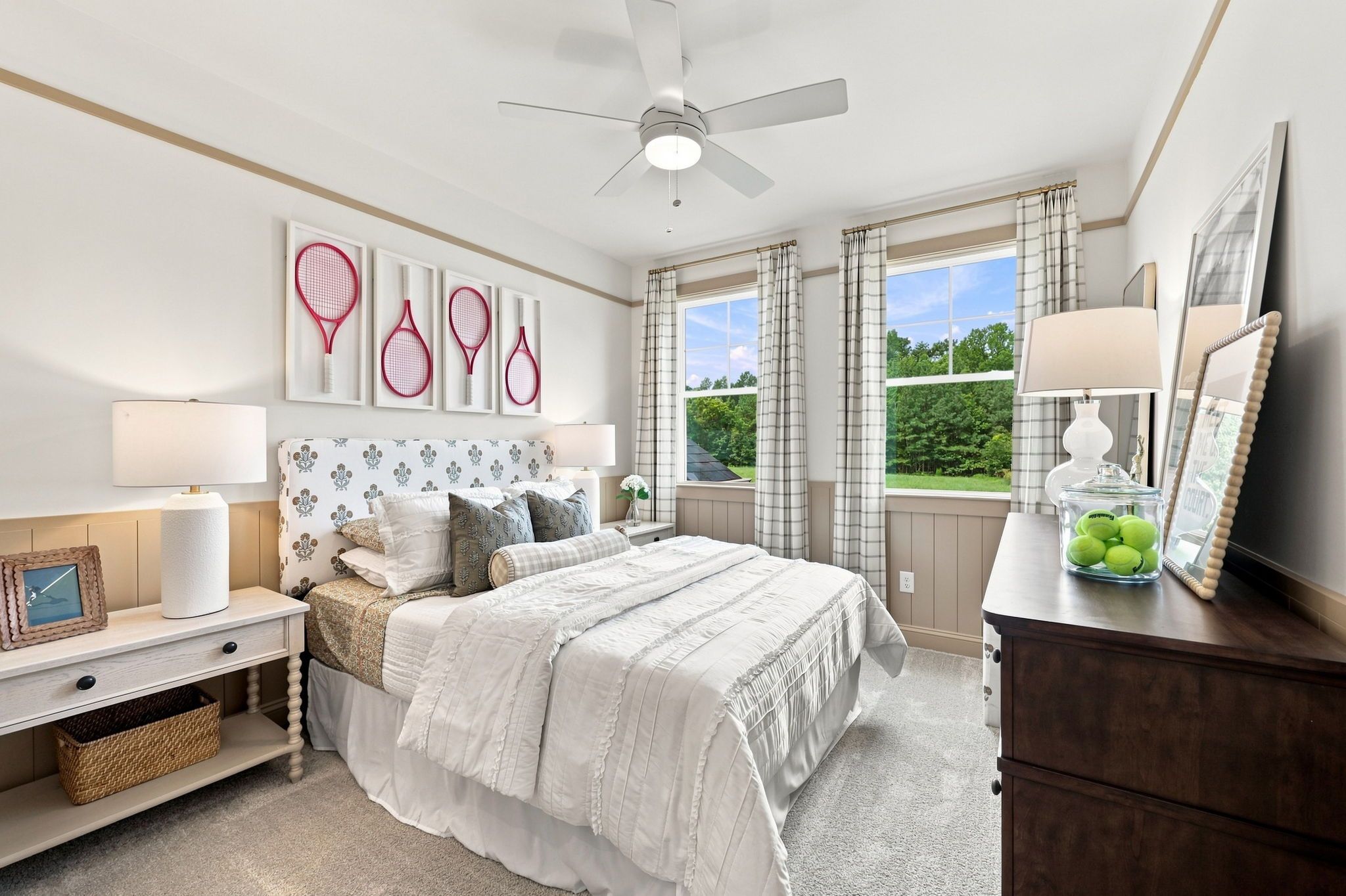 Bright bedroom in The Barrington C featuring a tennis-themed headboard, neutral wainscoting, and plush bedding.
