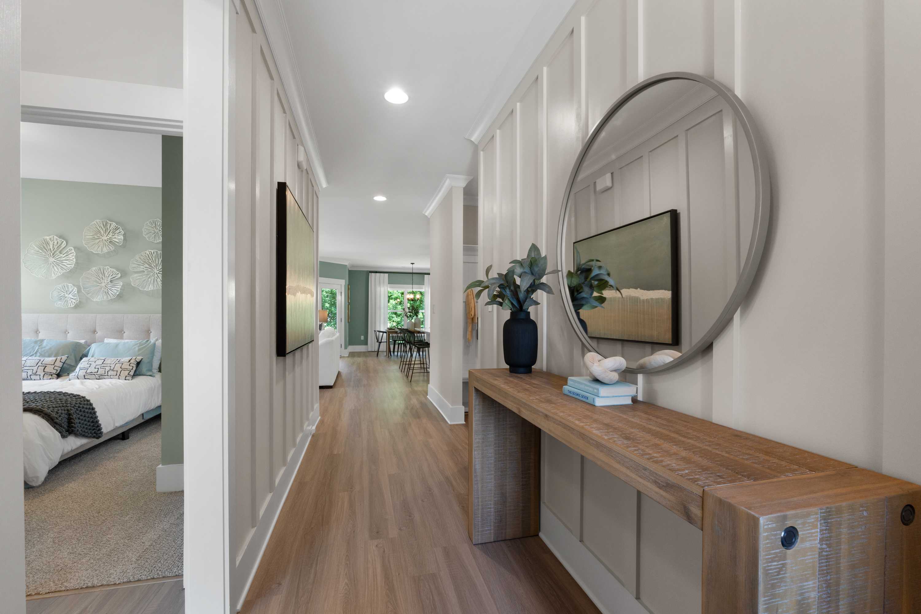 Spacious hallway with shiplap walls, round mirror, wooden console table and vase at Hollon Meadow in Decatur, Alabama by Davidson Homes