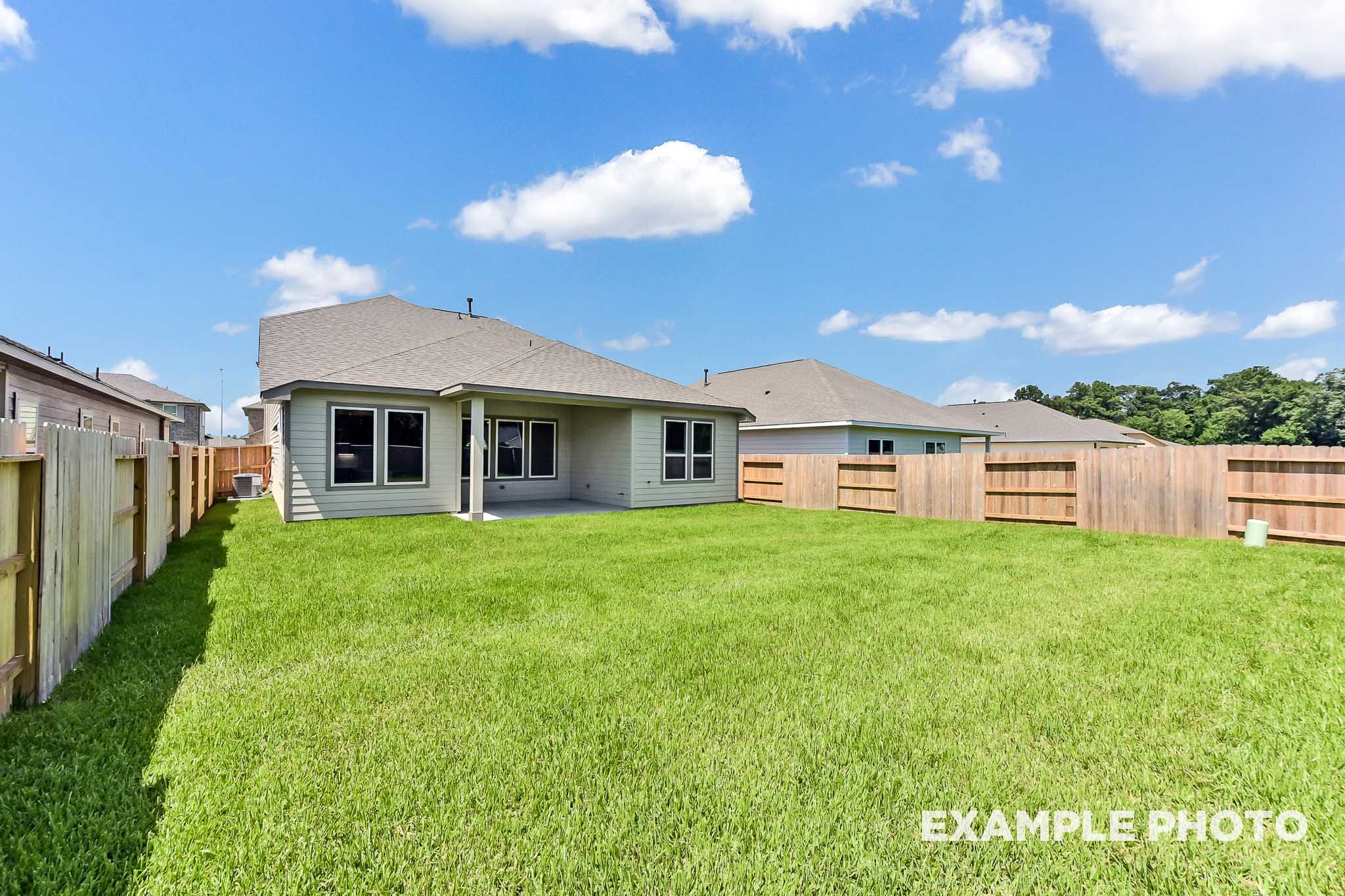 Rear view of The Sequoia A two-story home by Davidson Homes, featuring covered patio, spacious green backyard, and wood fence in Crosby Texas