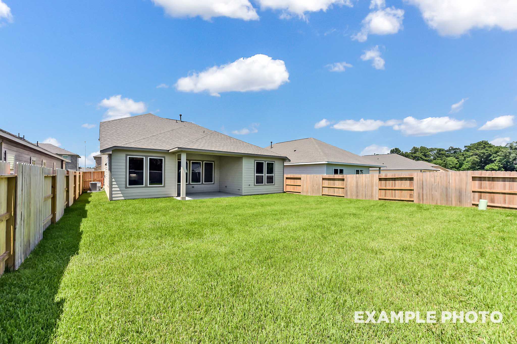 Rear view of The Sequoia A two-story home by Davidson Homes, featuring covered patio, spacious green backyard, and wood fence in Crosby Texas