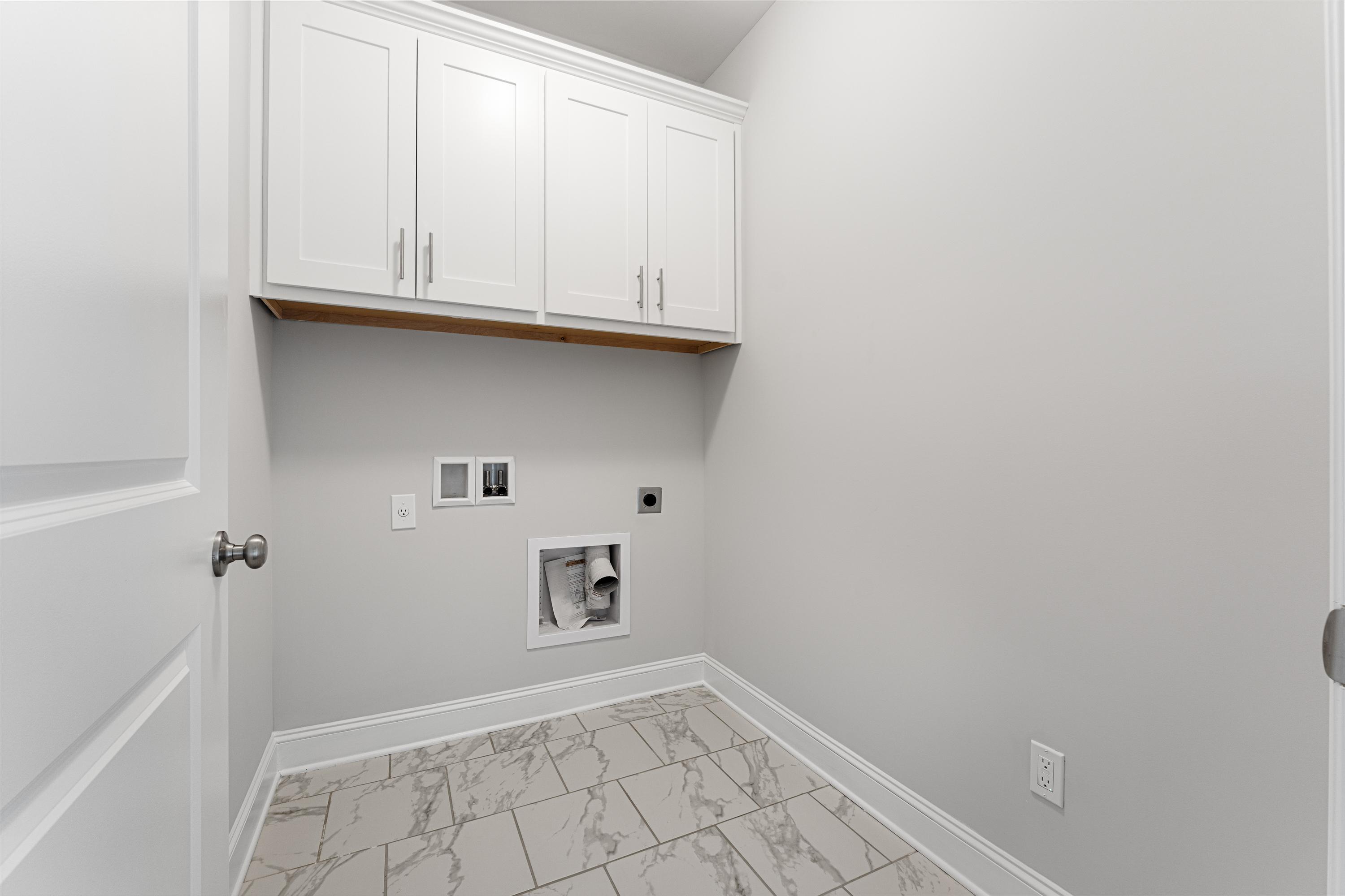 Spacious laundry room in The Copeland C featuring white upper cabinets, gray walls, washer-dryer hookups, and tiled flooring