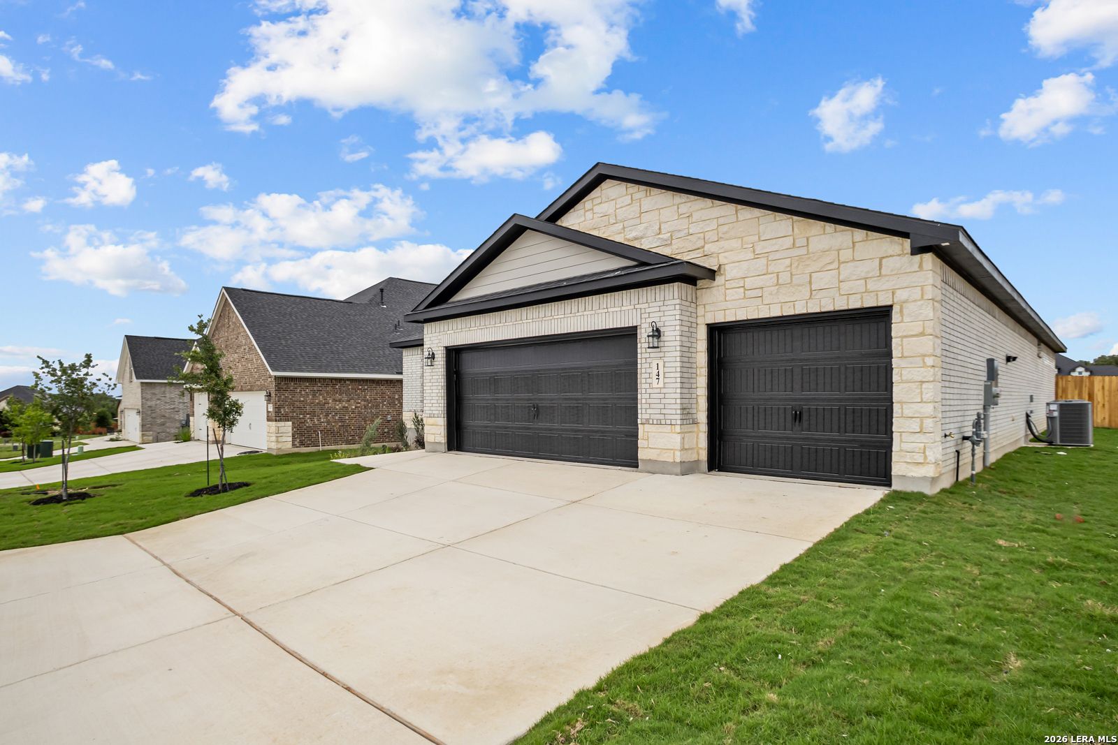 Exterior of a 1-story stone home with 2-car garage in The Reserve at Potranco Oaks, Castroville, Texas by Davidson Homes.