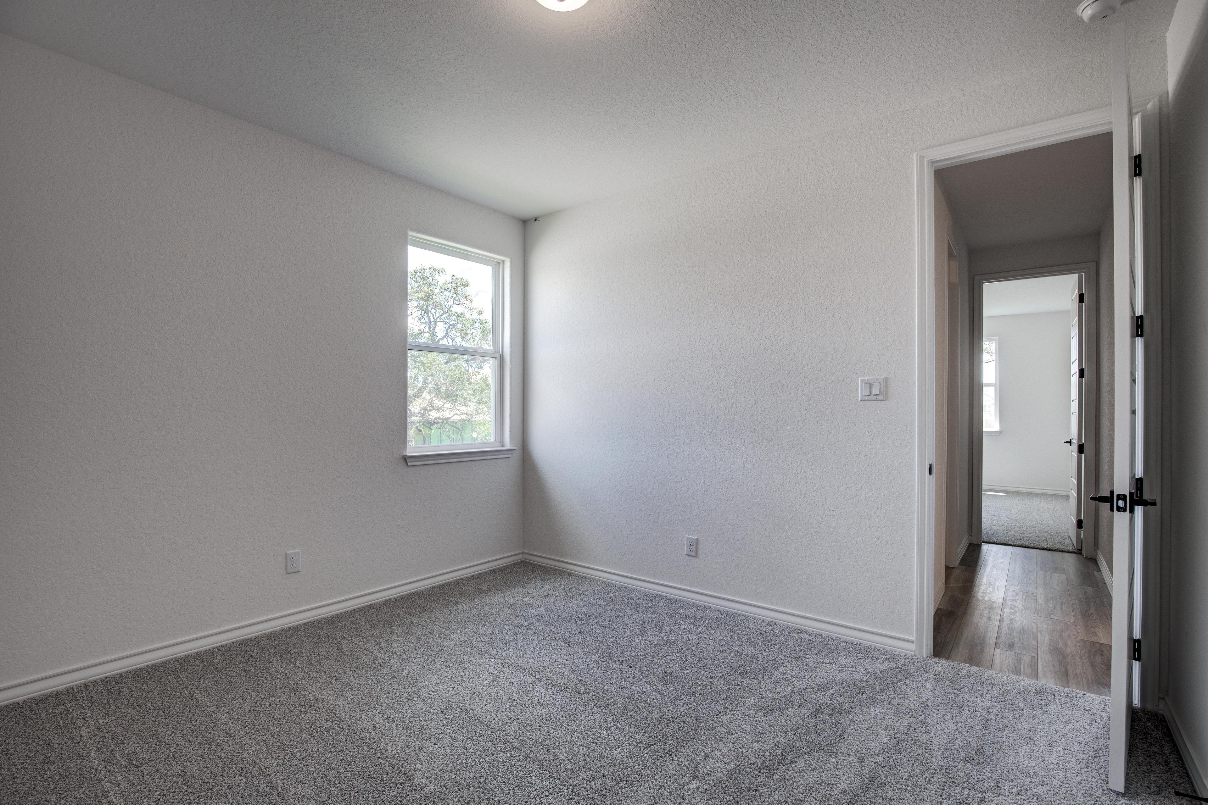 Spacious secondary bedroom in The Lanier floor plan with white walls, large window, gray carpet, and open doorway