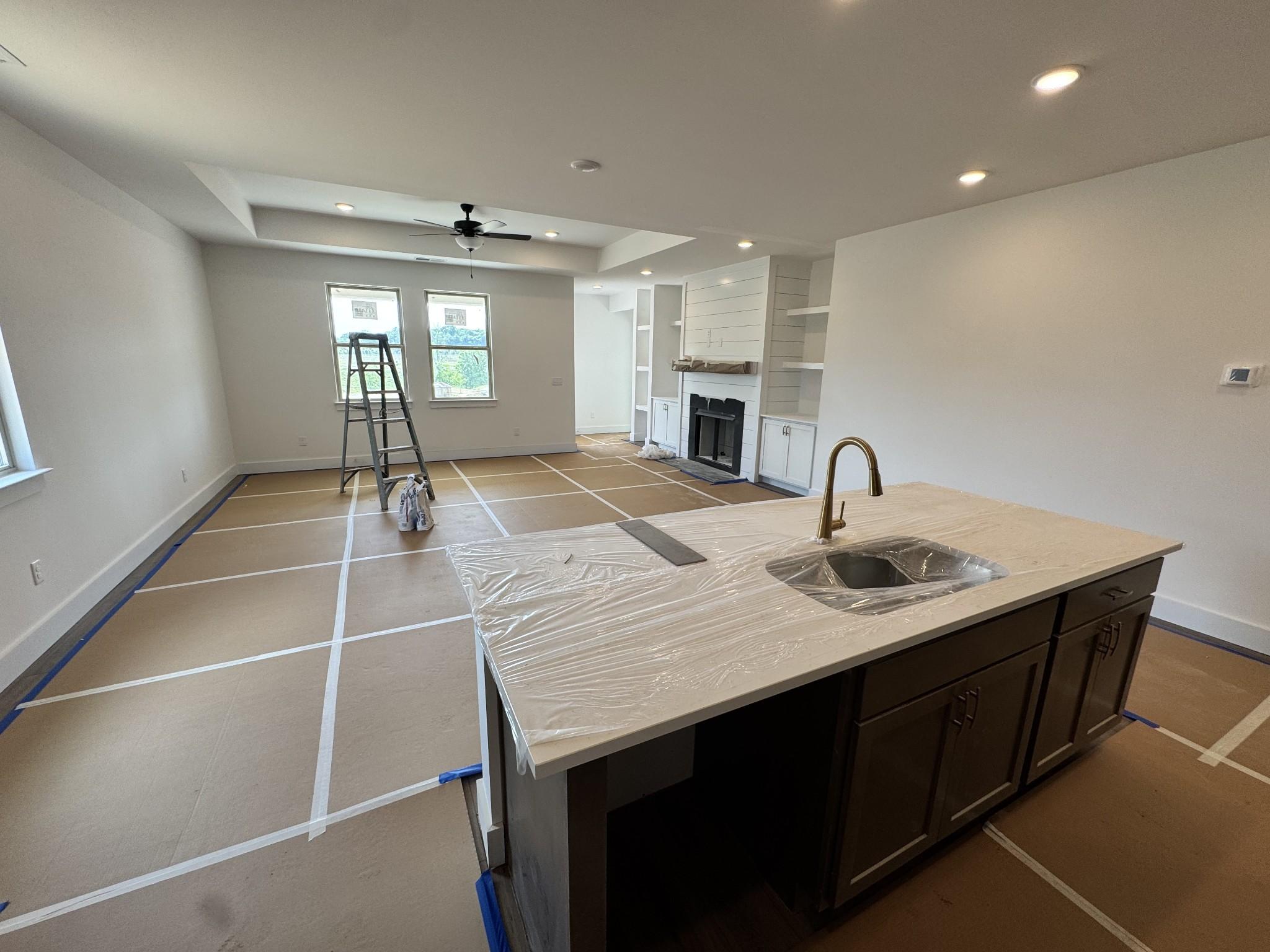 Open-concept living area with shiplap fireplace, protected quartz kitchen island, and ceiling fan in Davidson Homes Prairie C, Gallatin TN