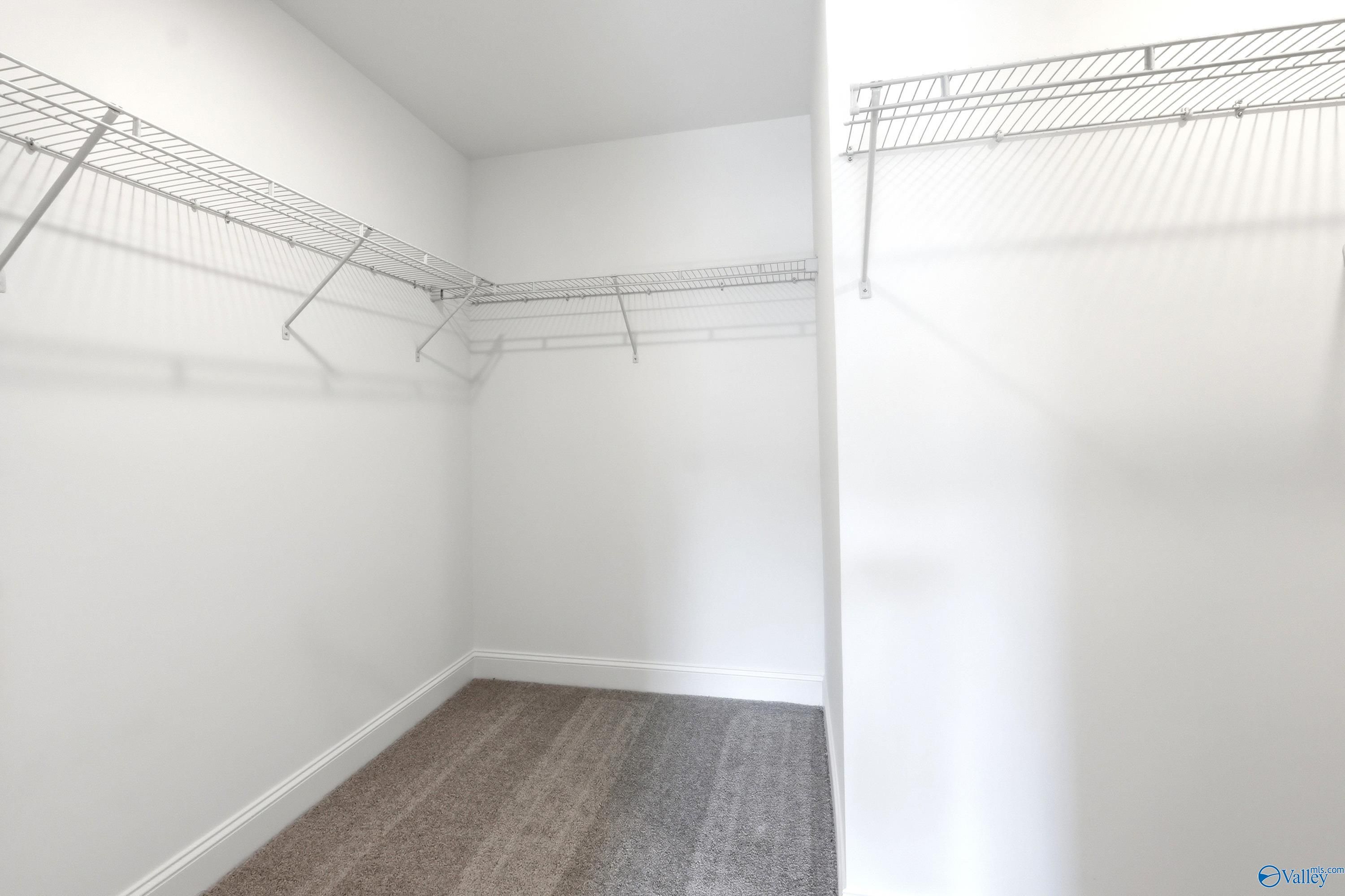 Walk-in closet with white wire shelving and plush carpet in The Russell A floor plan, Spragins Cove, Huntsville, Alabama.